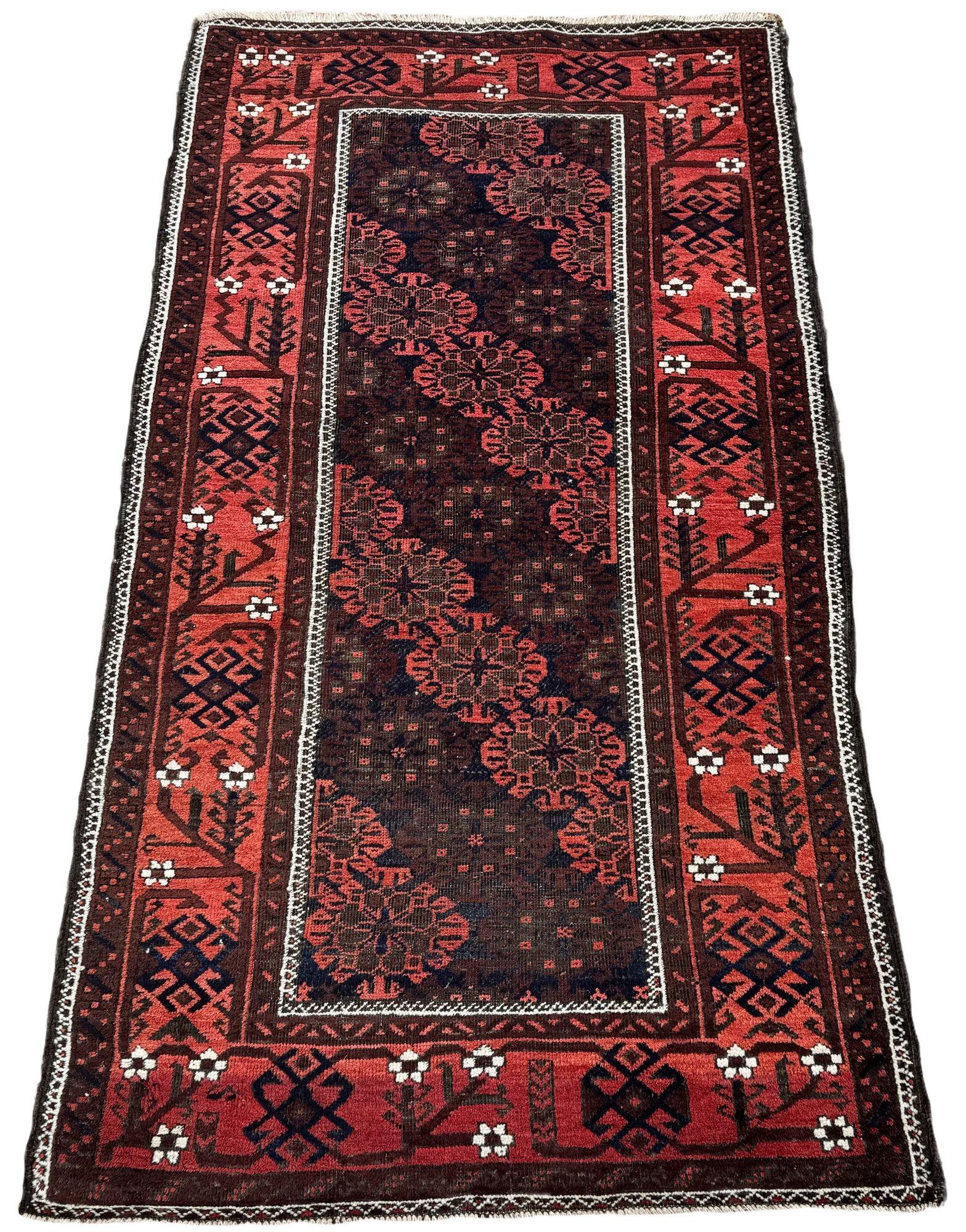 Un meraviglioso tappeto tribale antico, tessuto a mano dalla tribù nomade dei Belouch nel 1900 circa. Il tappeto presenta un insolito disegno all over di grandi teste di fiori ripetute su un campo grigio antracite circondato da un bordo in