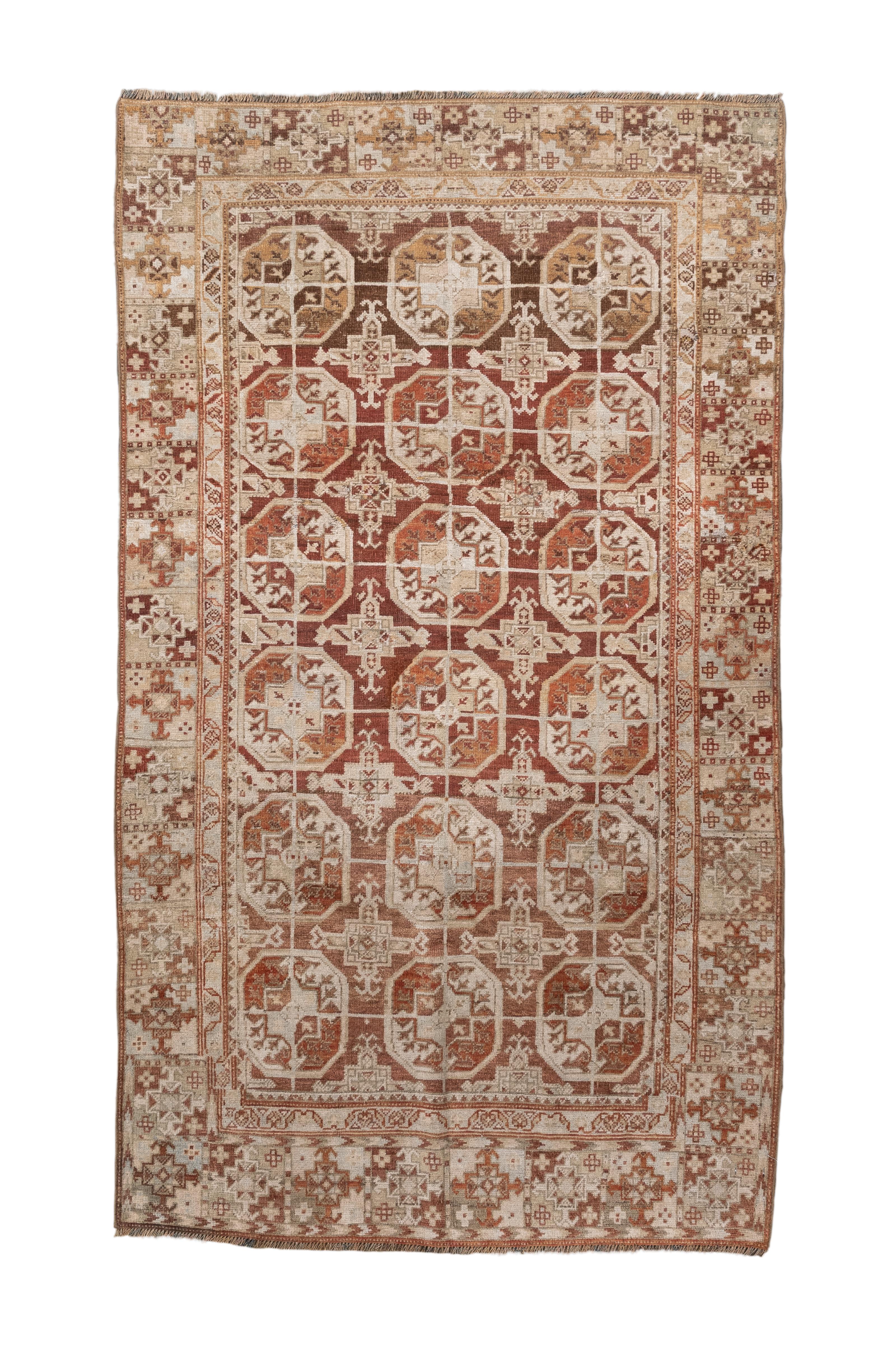 This antique Belouch rug features a striking and sophisticated tribal design rendered in a rich palette of earthy reds, soft ivories, and warm browns. The field is adorned with a series of geometric medallions framed by intricately detailed borders,