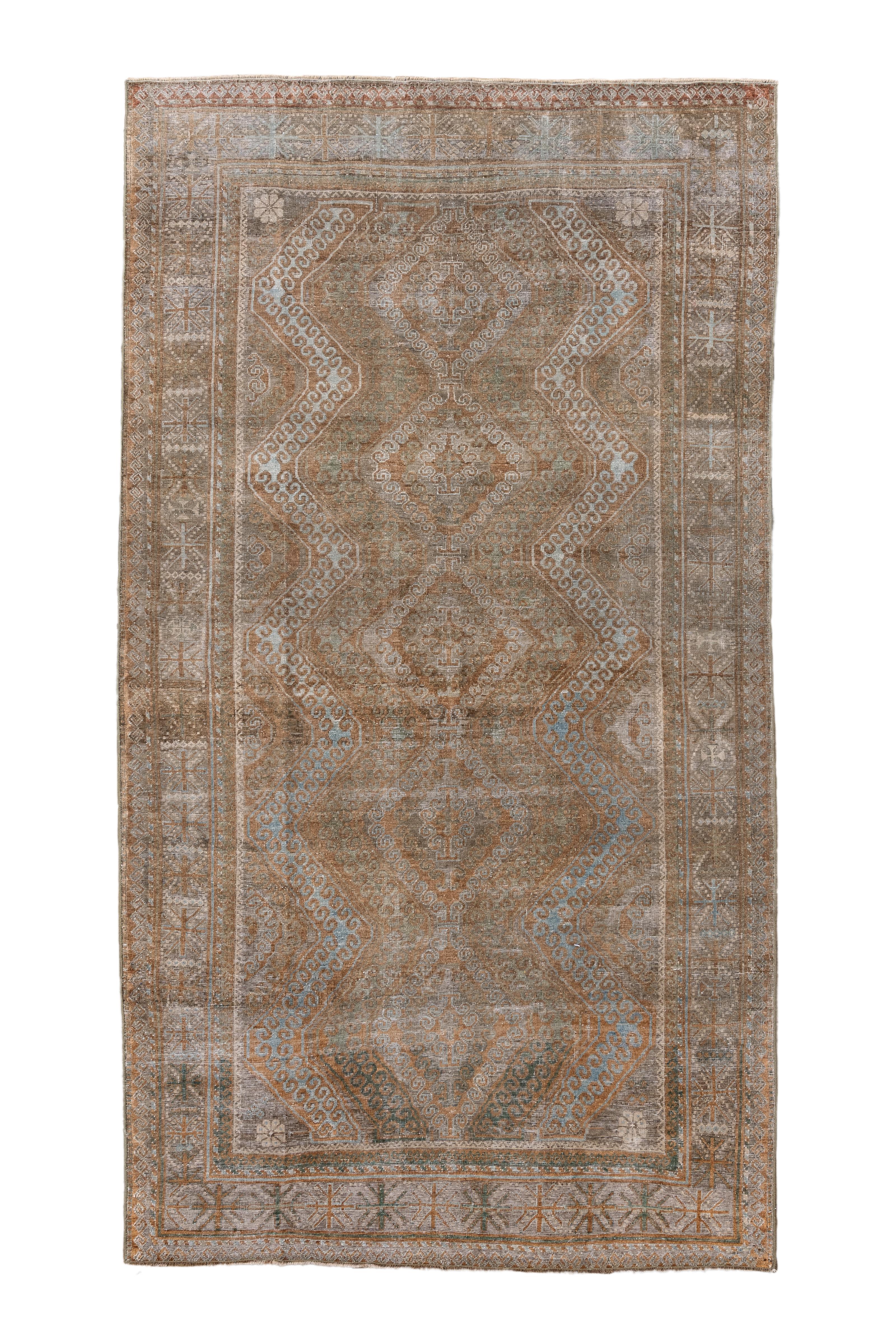 Esta antigua alfombra Belouch, que mide 1,5 m × 1,9 m, presenta una llamativa estética tribal con un raro e hipnotizador diseño geométrico de medallones con motivos de rombos escalonados. La paleta de topos apagados, óxido suave, azul helado y verde