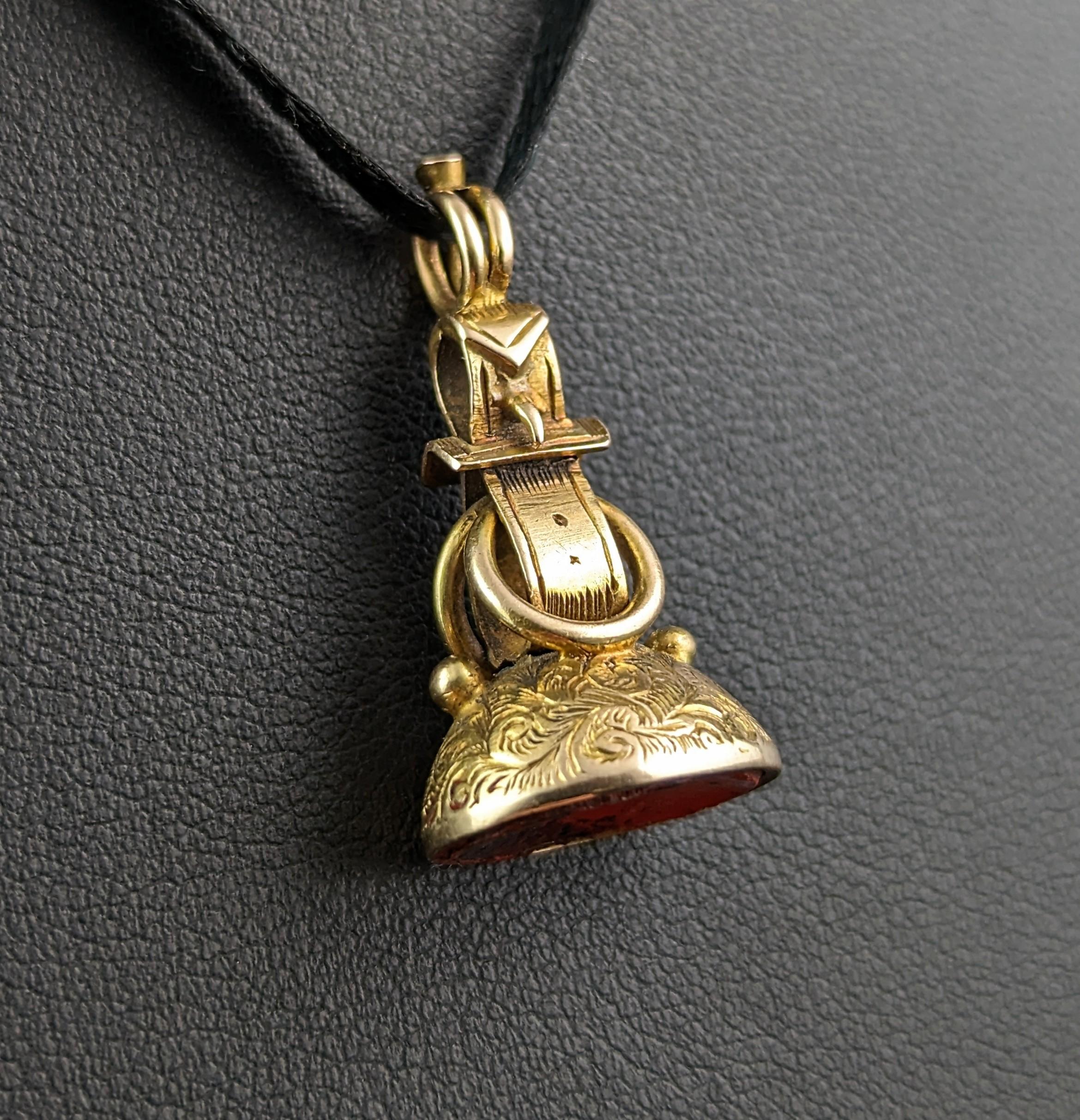 This antique 9ct gold seal fob has a wonderful and unusual design which is really very charming!

It is designed as belt and buckle with a heavily chased domed base, the attention to detail is really very good on this piece and it has been expertly