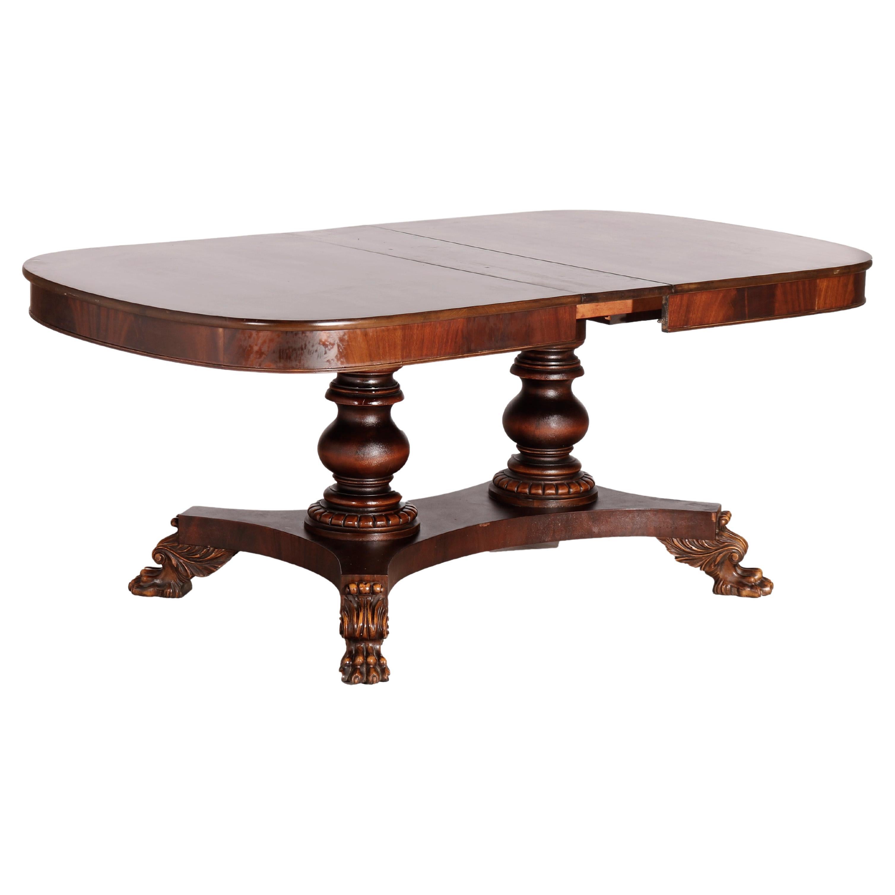 An antique American Empire Berkey & Gay extension banquet dining table offers mahogany construction with deep skirt over double pedestal base and raised on carved paw feet, includes three 10