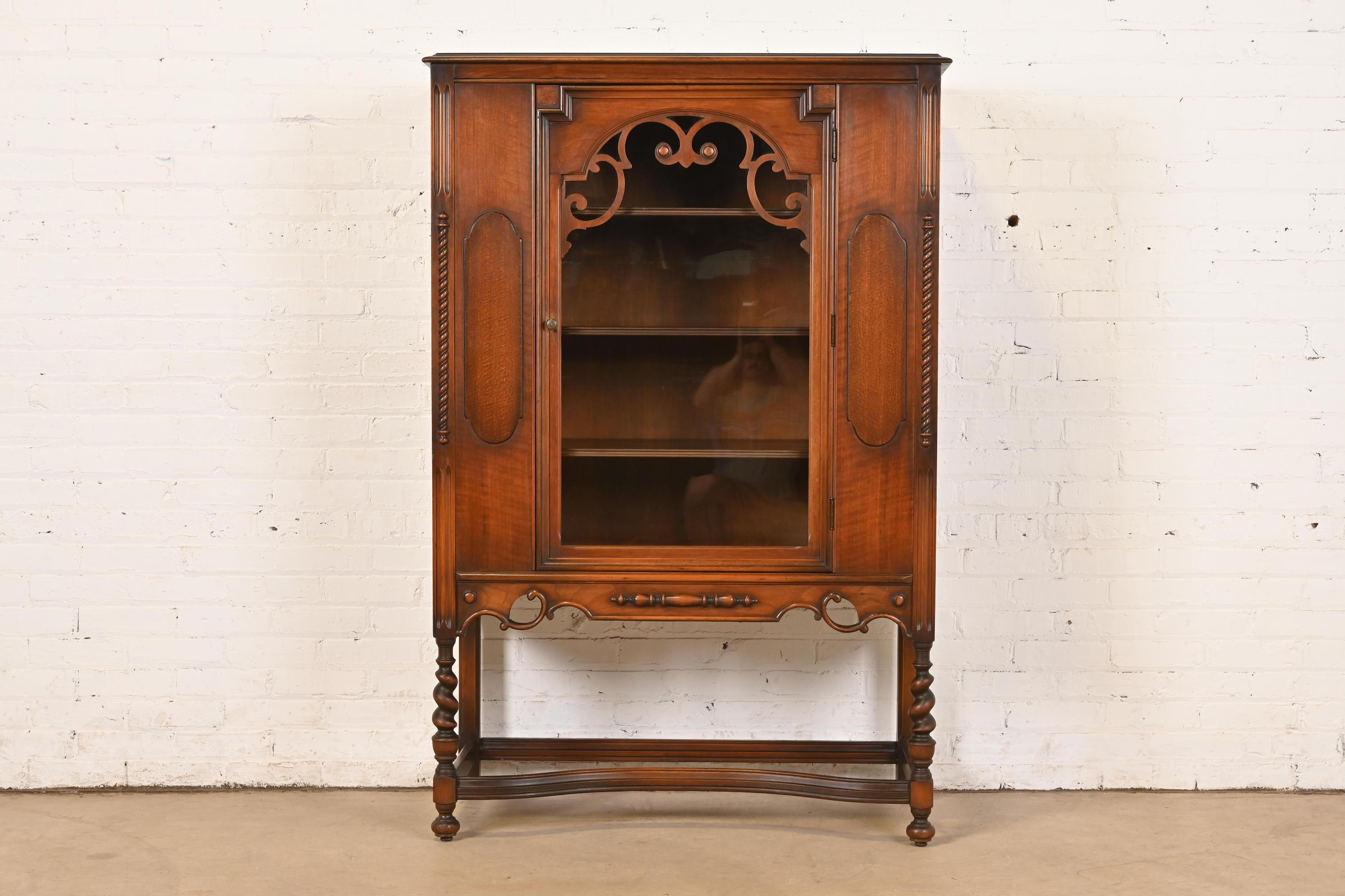 An exceptional English Jacobean style bookcase, china hutch, or bar cabinet

In the manner of Berkey & Gay

USA, Circa 1920s

Carved walnut, with burl wood panels, glass front door, and original brass hardware.

Measures: 40