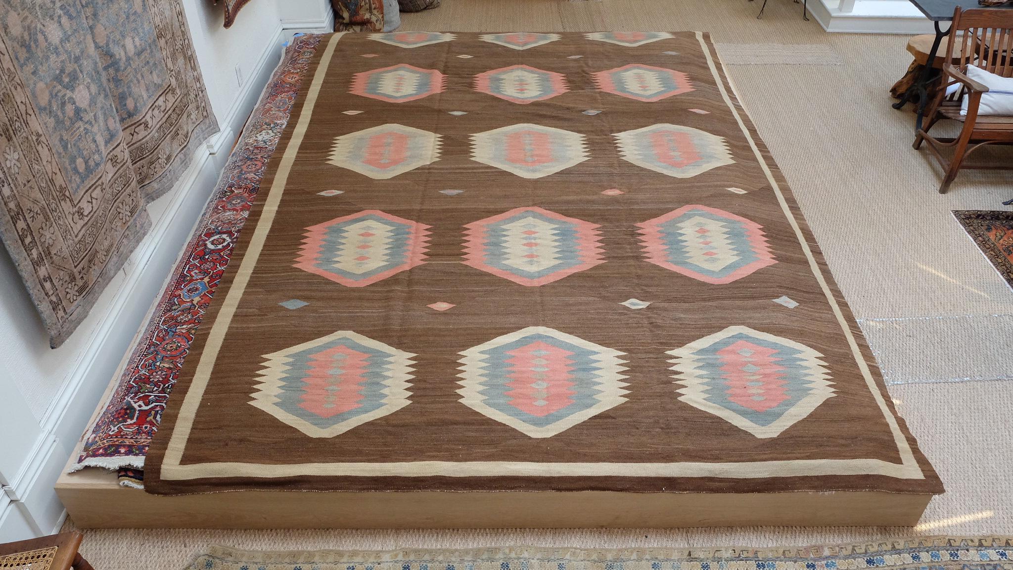 A finely woven Kilim in a rare size and coloration. An unusual rich camel brown field and oversized design in soft pink, gray and ivory. In very good condition with a nice weight. Secured sides and ends. Naturally dyed and handwoven in the light