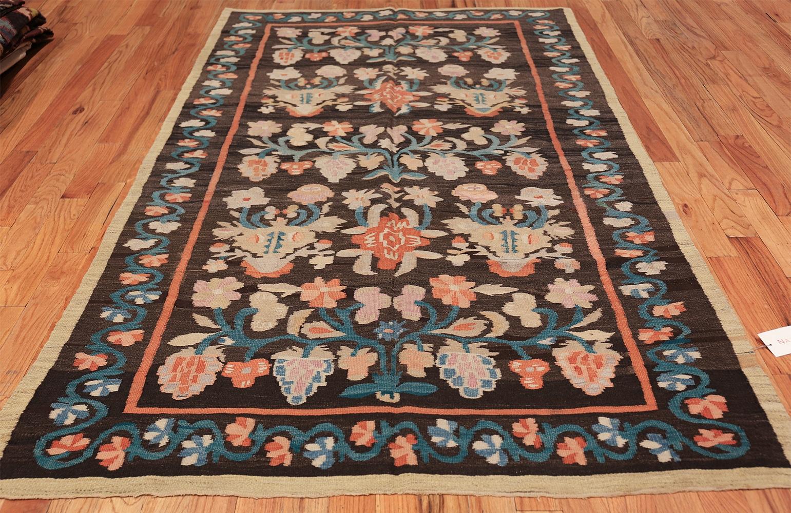 Antique Bessarabian Kilim rugs, Origin: Turkey, circa 1900. Size: 5 ft 2 in x 9 ft (1.57 m x 2.74 m). 

A lovely array of floral sprays in soft green-blue, mauve, pale apricot, and soft red floats happily across the deep chocolate ground of this