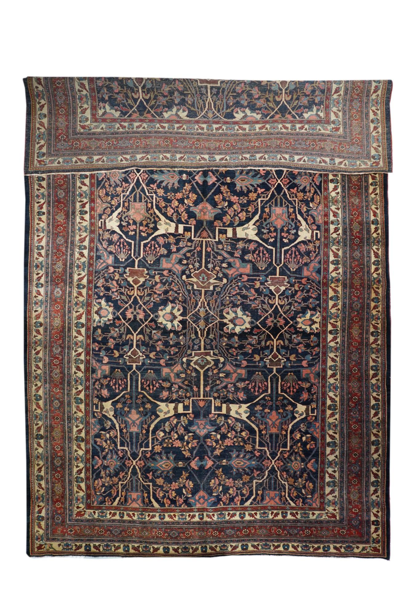 Cet exemple à fond indigo foncé présente des arabesques fourchues caractéristiques en écru plutôt qu'en rouge, plus habituel, ainsi que des palmettes à pétales paresseux en ivoire. Détails en rose et bleu clair. Bordure principale rouge de rosettes