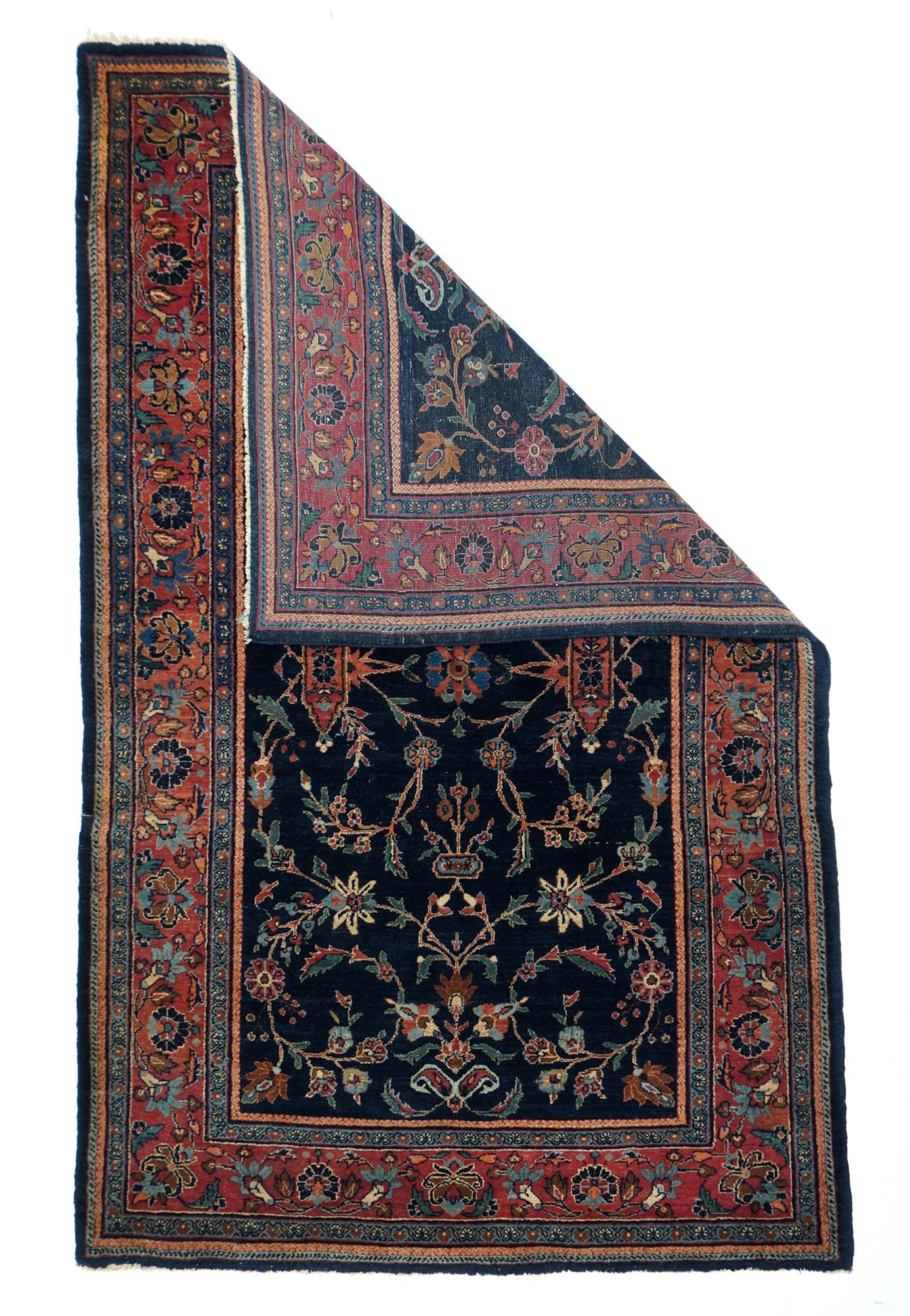 The navy indigo-sourced ground of this centralized pattern west Persian Kurdish urban scatter shows a small focal rosette surrounded by vines, cartouches, saz leaves, and lesser rosettes, all within an abrashed red-rose border of vinery and