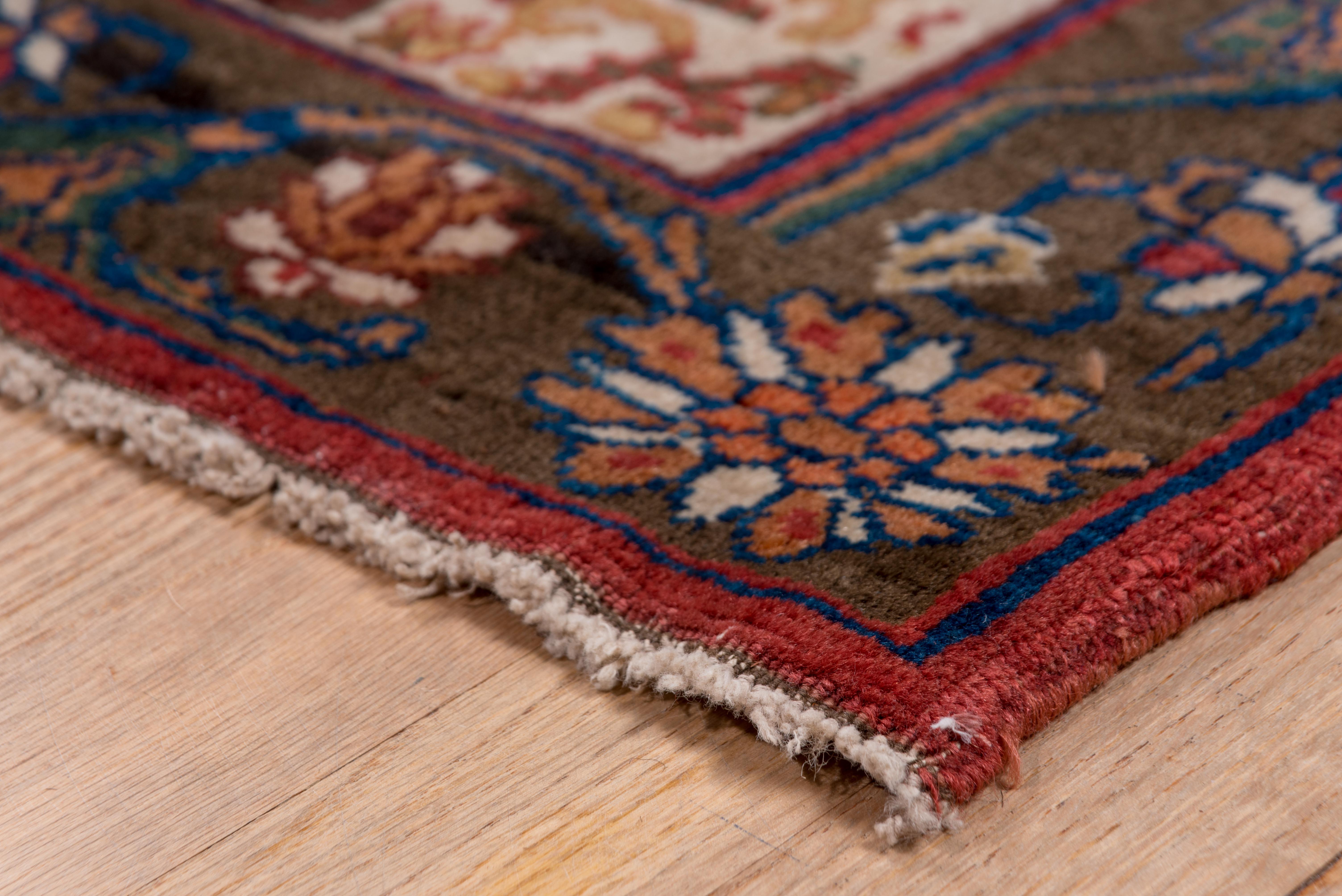 This antique Bidjar rug showcases a meticulous allover floral repeat pattern composed of stylized blossoms and vinery set against a pale rose-beige field. Rich tones of indigo, ruby, emerald, and ivory form dense flower clusters outlined by sinuous
