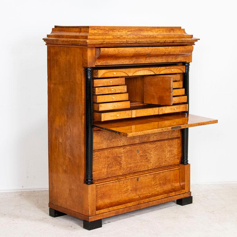 This stunning secretary is made of birch wood with a shellac finish which brings the wood to life. The wood grain appears to glow from within, and the detailed drawers and classic Biedermeier black columns complete the overall classic look. The