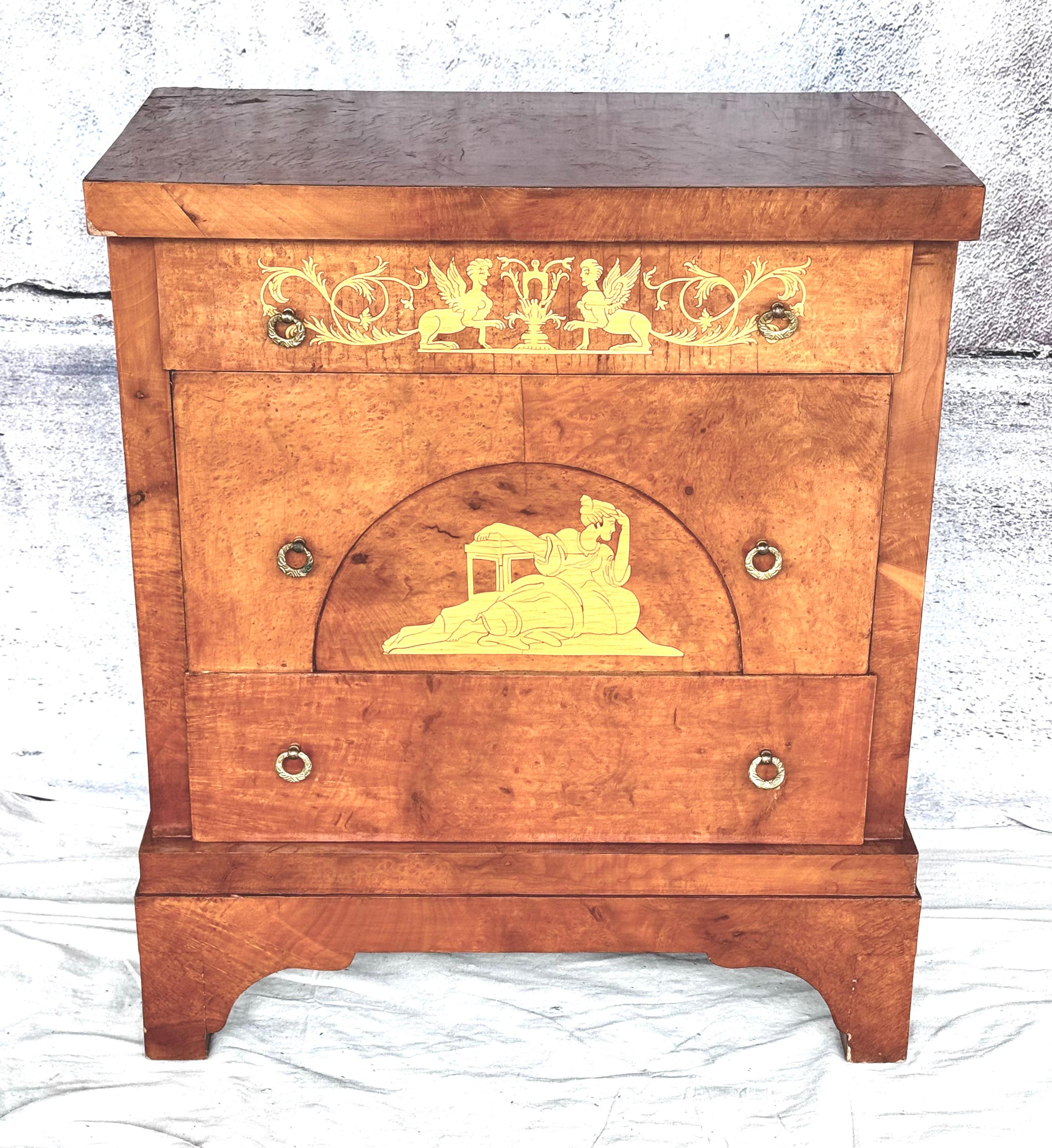 Eine schöne figurale Kommode aus dem späten 19. und frühen 20. Jahrhundert aus dem Biedermeier mit Intarsien. Kommode mit drei Schubladen mit Satinholzeinlagen. Die obere Schublade ist mit einem Paar sich gegenüberstehender Greife eingelegt, aus