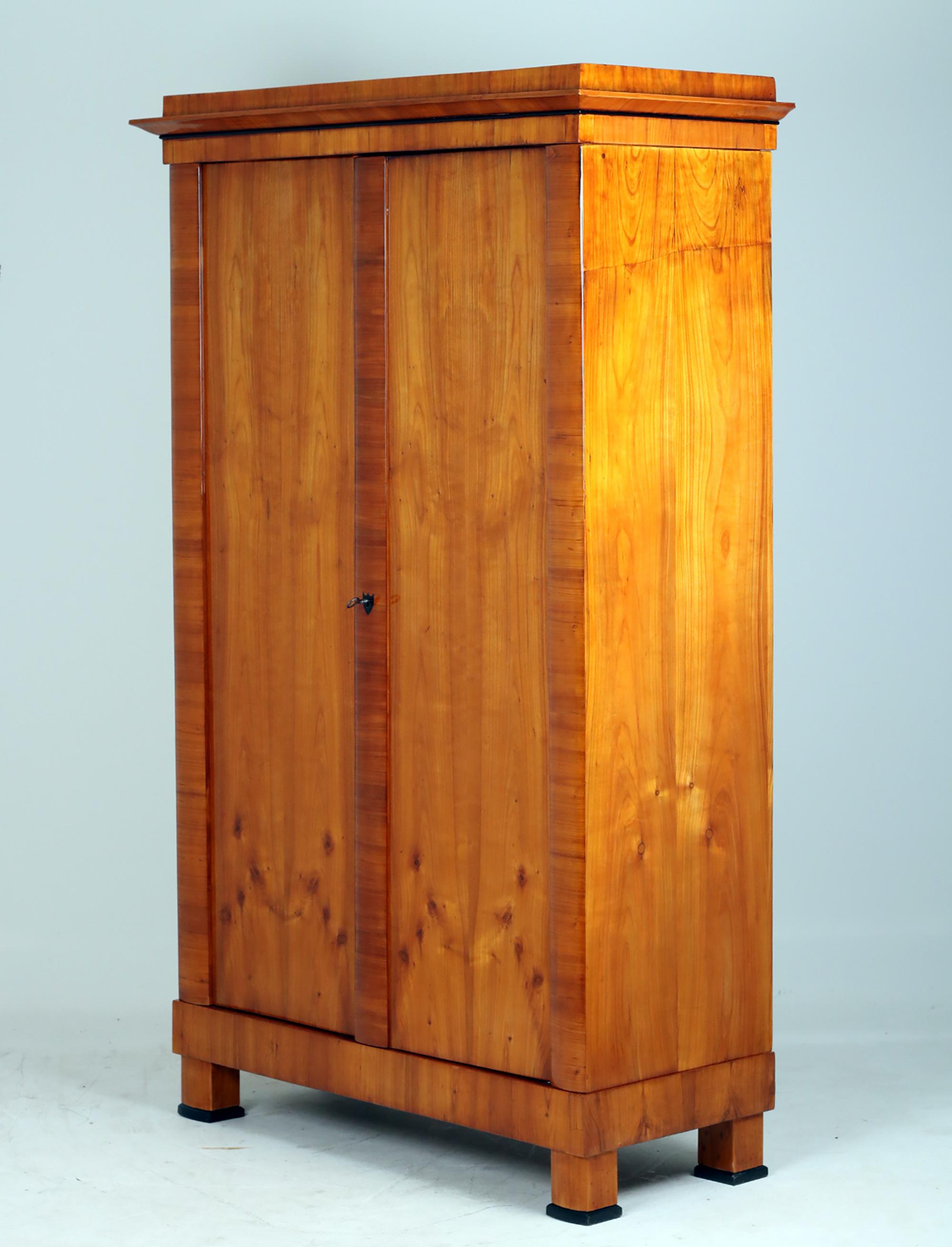 Biedermeier Cabinet, Austria 1830

Original two-door Biederemeier cupboard veneered in cherry.
Classic legs and an original lock.
The strike bar and the pilaster strips are cross-veneered and curved to the front. The escutcheon in the shape of a