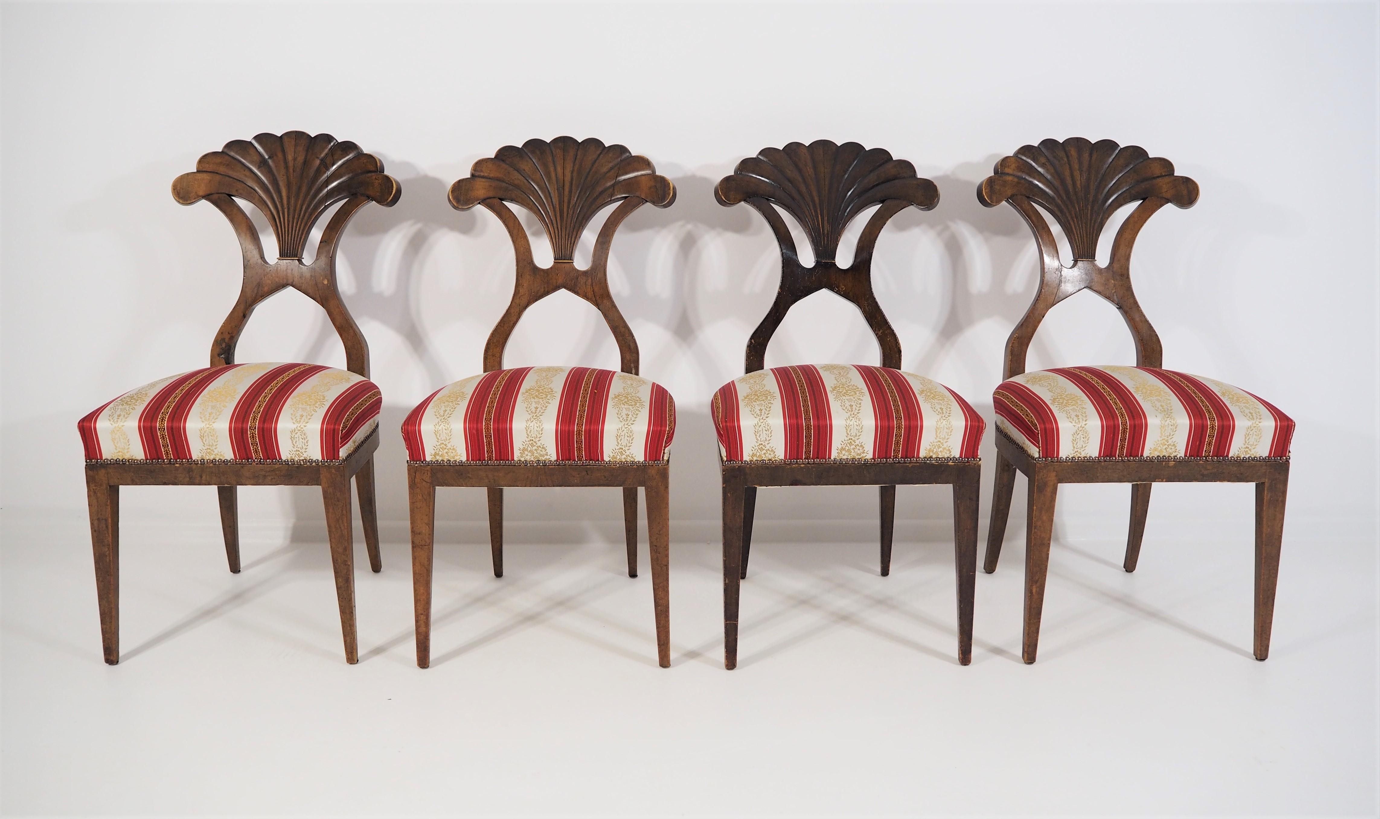 4 Biedermeier dining chairs. On elegant legs, shell-shaped backrests with walnut veneer. Established in the 19th century. Material: walnut. Dimensions: (H x W x D) 92 x 45 x 55 cm.