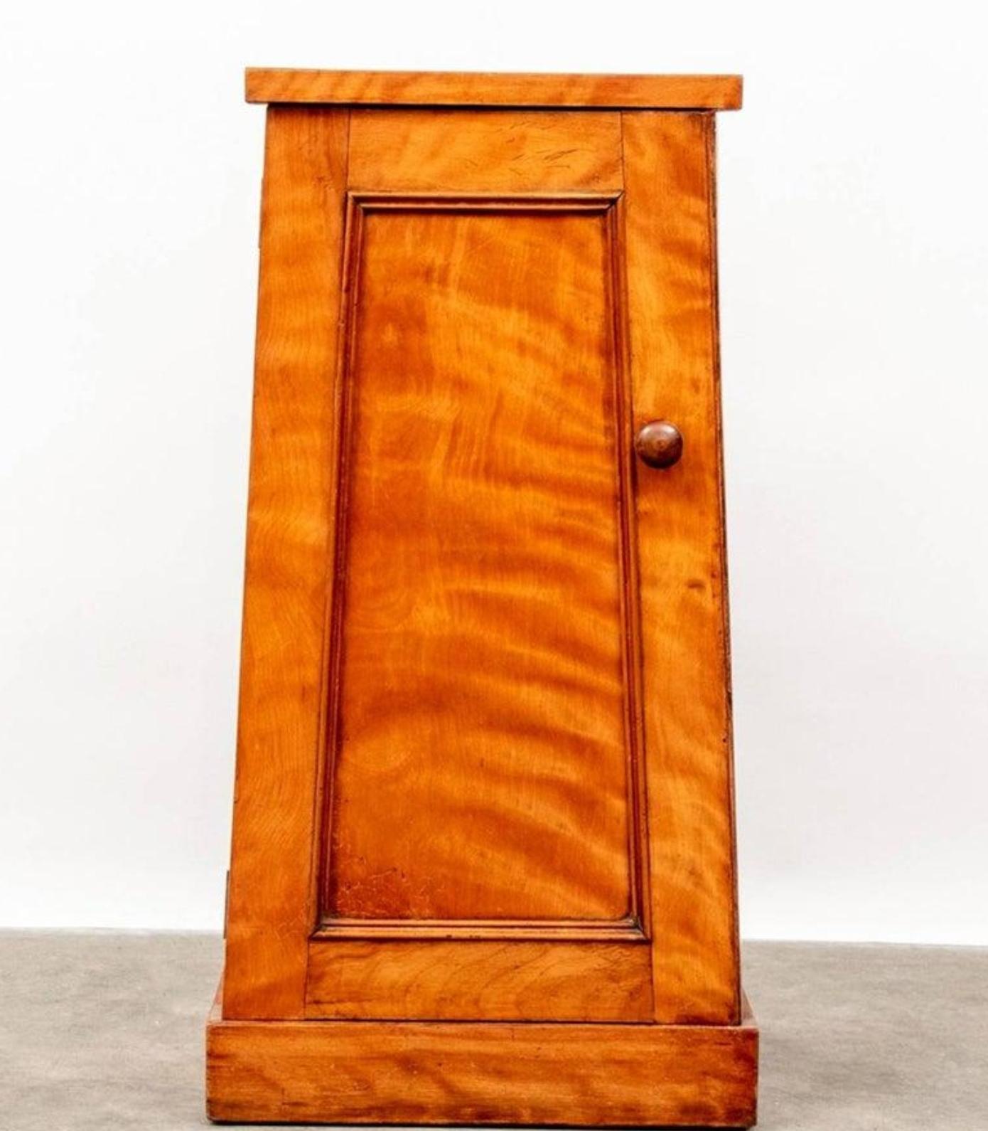 A scarce antique European Biedermeier style single door pyramid bedside cabinet. Hand-crafted, featuring strong, high quality craftsmanship and solid wooden construction, exceptionally executed in rich exotic and lustrous highly figured satin