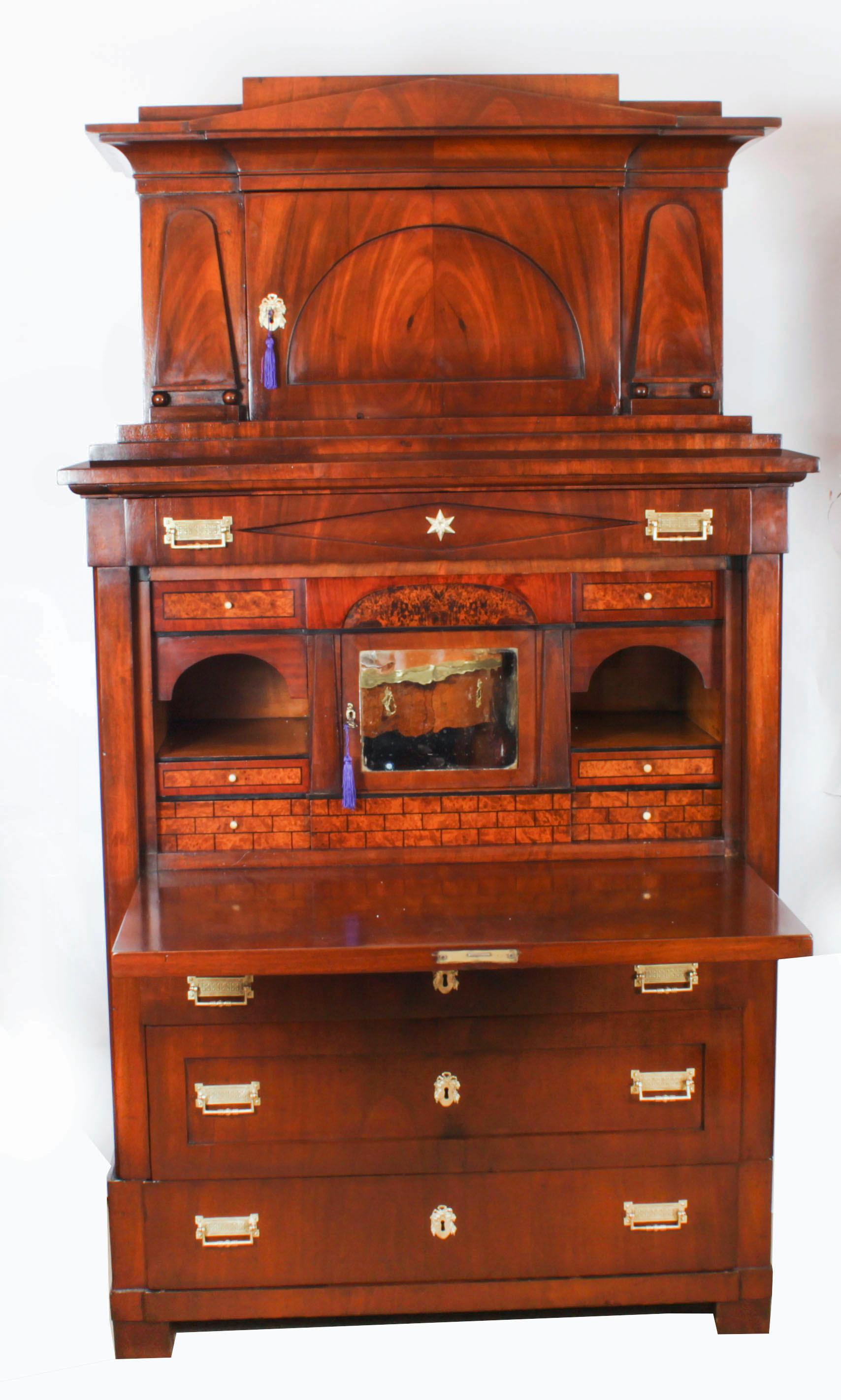 Un magnifique secretaire abattant architectural Biedermeier en acajou flammé, datant d'environ 1840.

La partie supérieure est ornée d'une corniche en saillie au-dessus d'une porte cintrée à panneaux, entourée de montures façonnées en applique. La
