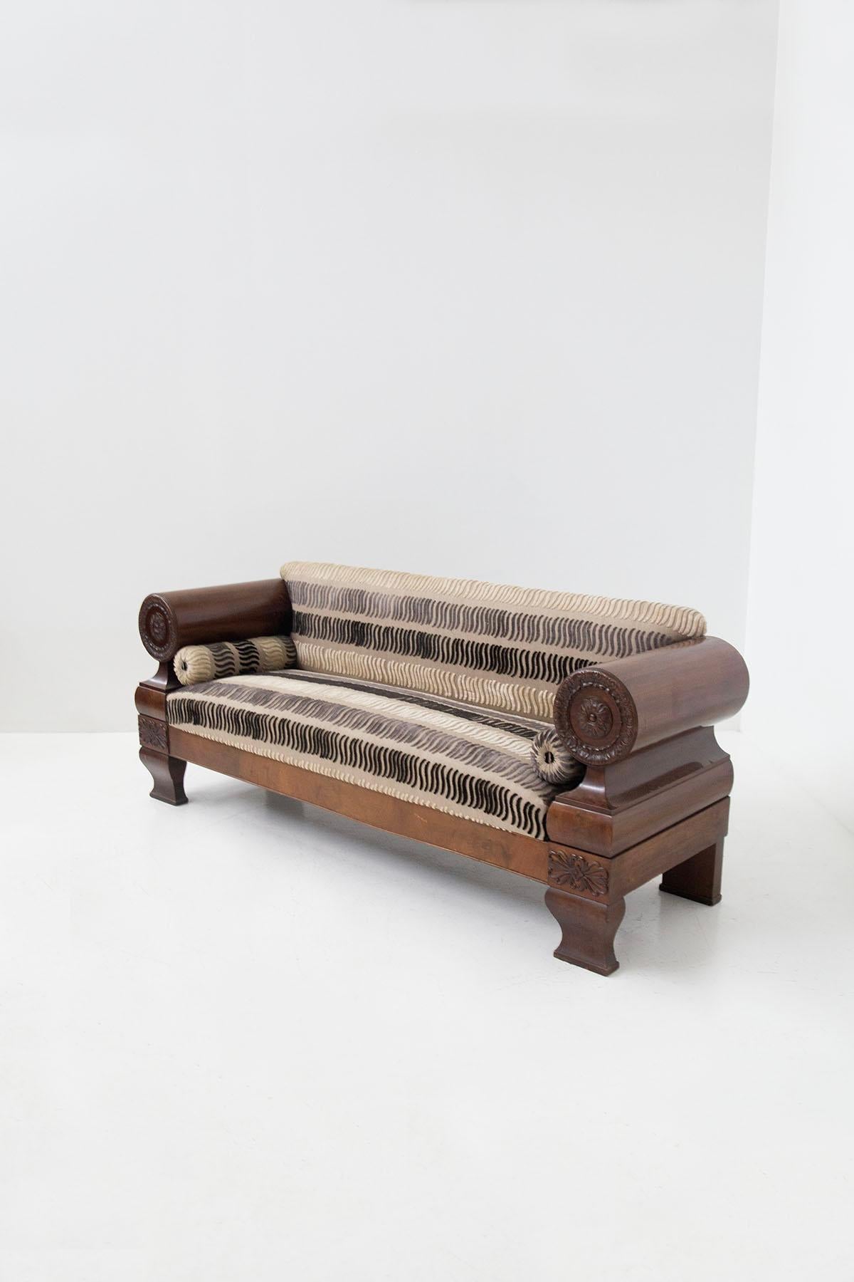 Impressive Biedermeier sofa of Northern European origin from the early 1900s. The majestic sofa features a colossal wooden frame with several special features. We notice at the sides two large wooden arm rests with a finely carved wood rosette of