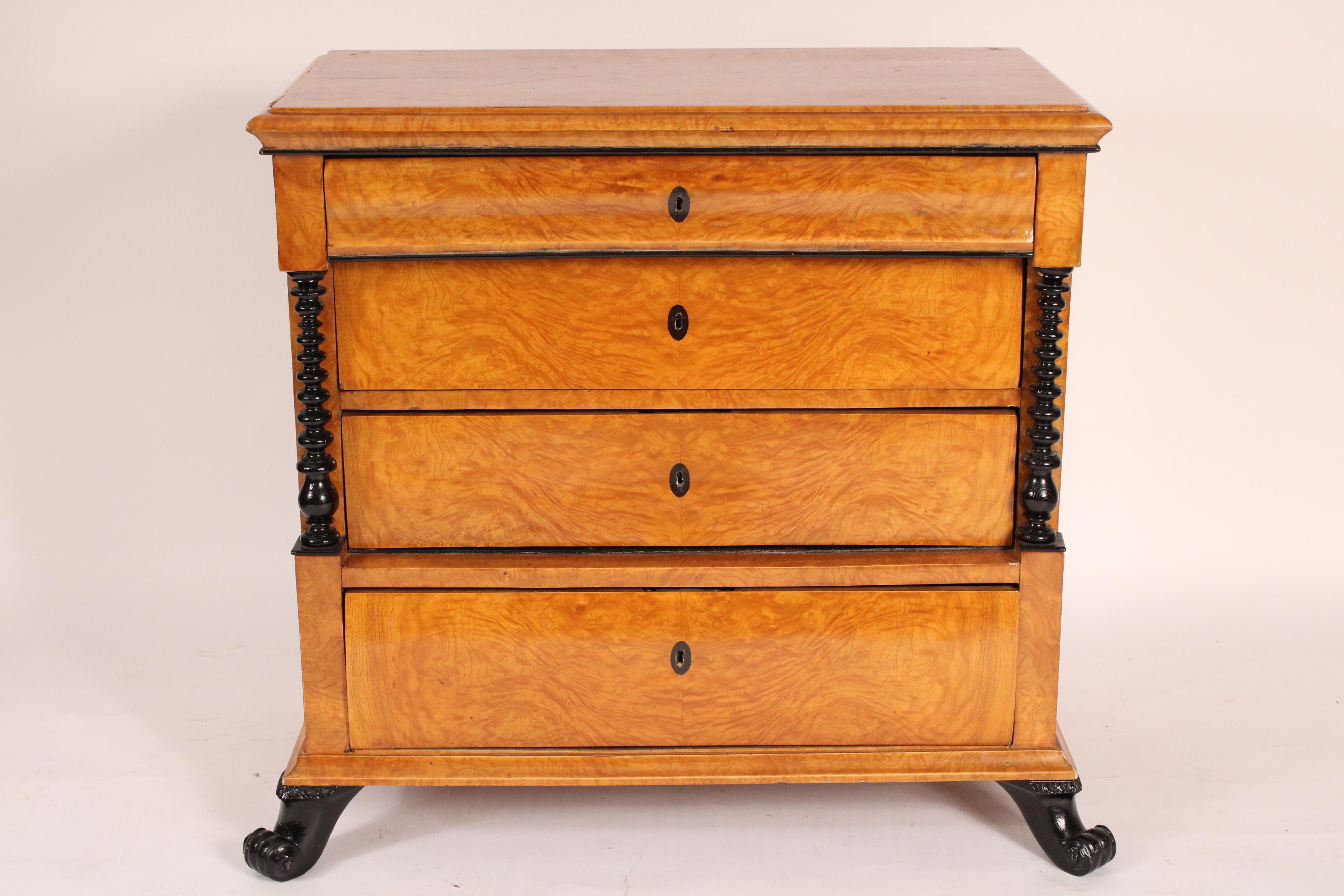 Antica cassettiera Biedermeier in betulla con riflessi ebanizzati, XIX secolo. Con un piano leggermente rettangolare con bordi anteriori e laterali modanati, sotto ci sono quattro cassetti, i due centrali affiancati da colonne ebanizzate tornite a