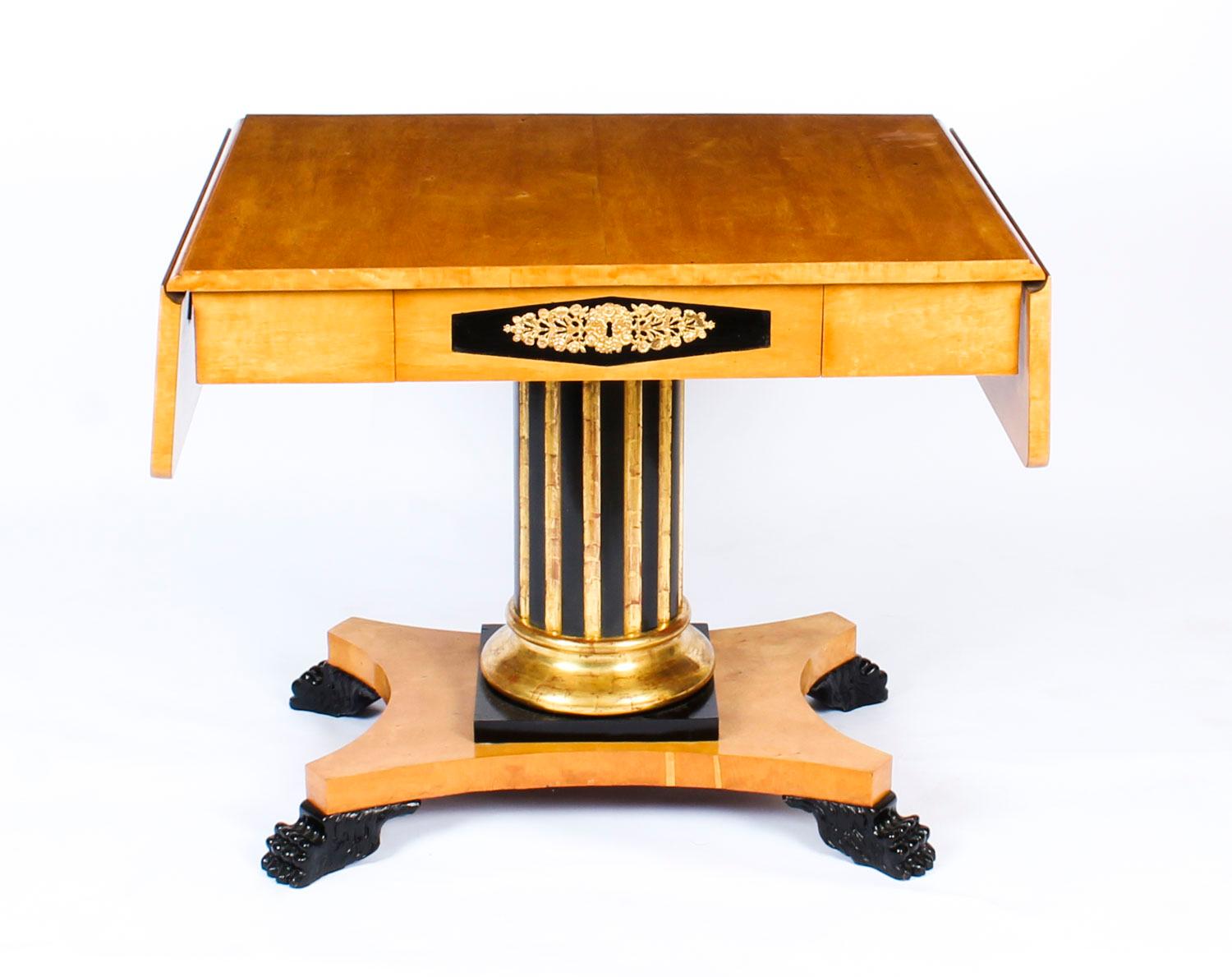 This is a stylish antique Swedish birch Biedermeier sofa table with ebonized detail, circa 1820 in date.
 
The table features a rectangular top with a drop flap to each side above a useful frieze drawer. It stands on a gilt and ebonized fluted Doric