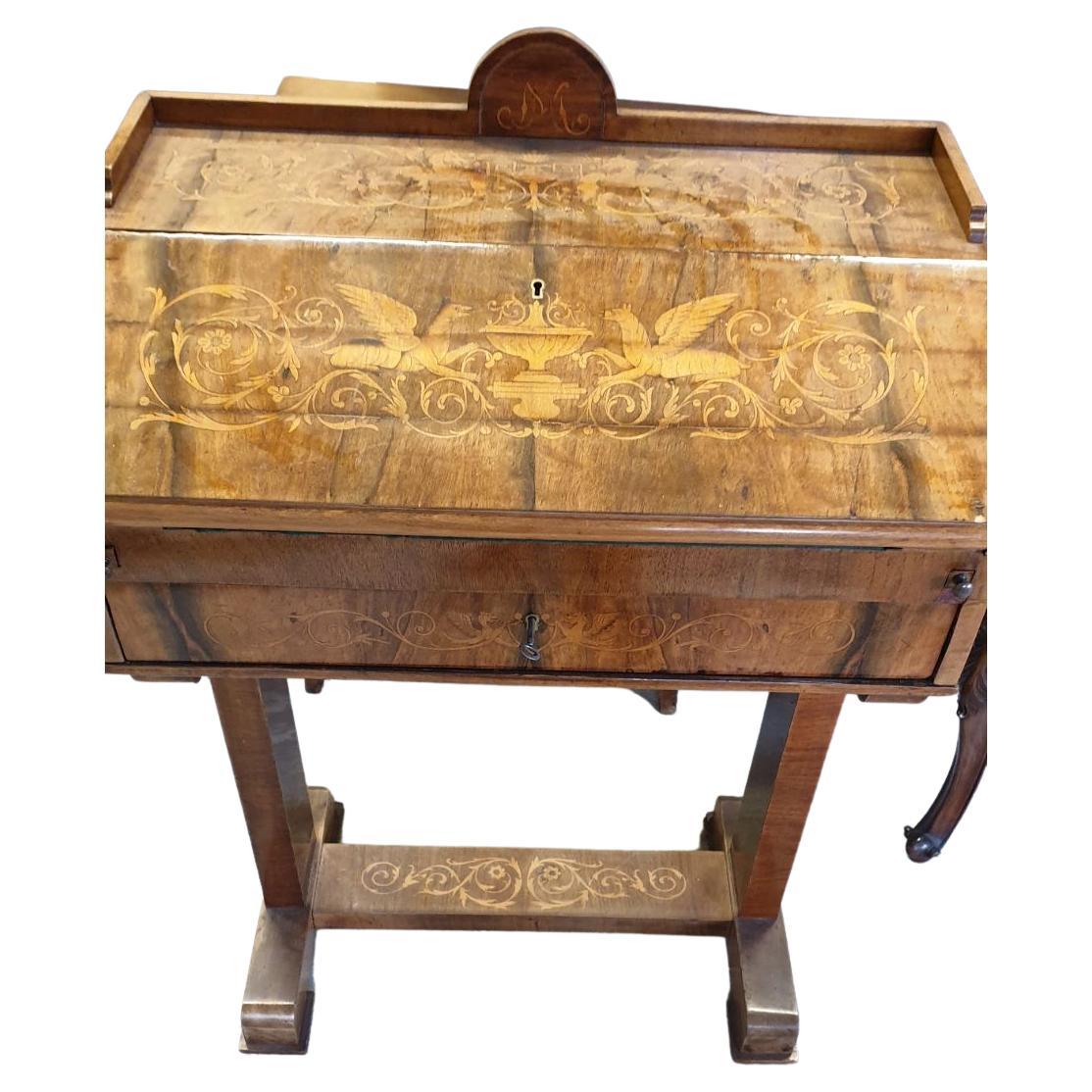 We present to you this special small secretaire table in Biedermeier style.
This piece of furniture is richly decorated with fine marquetry.
With its elegant silhouette and beautiful patina, this 20th-century Biedermeier era small table secretaire