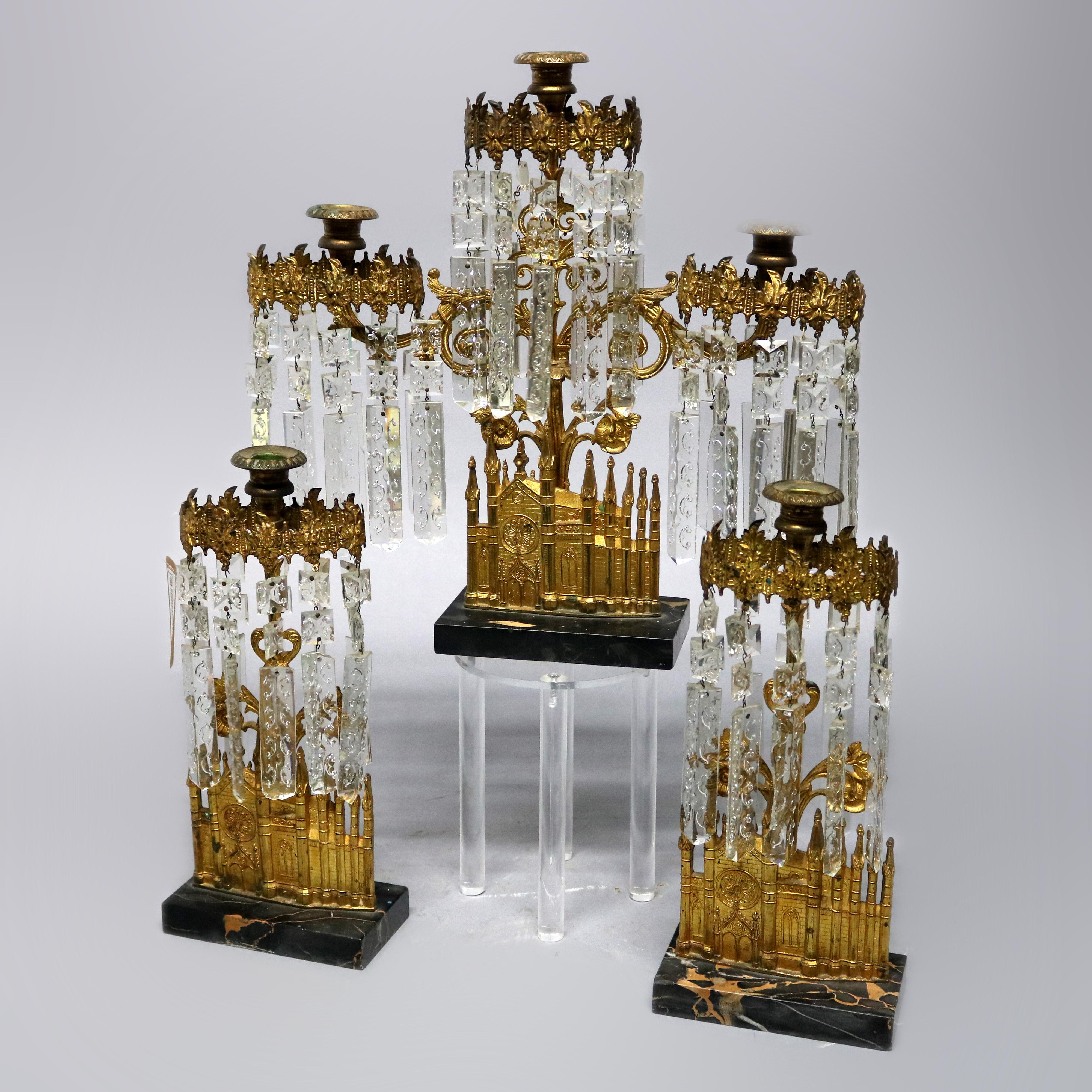 An antique garniture girandole set offers gilt bronze architectural casting of Bigelow Chapel in Boston, MA surmounted by tree form candelabra with scroll and foliate decorated hanging cut crystals throughout and mounted on marble bases, gothic