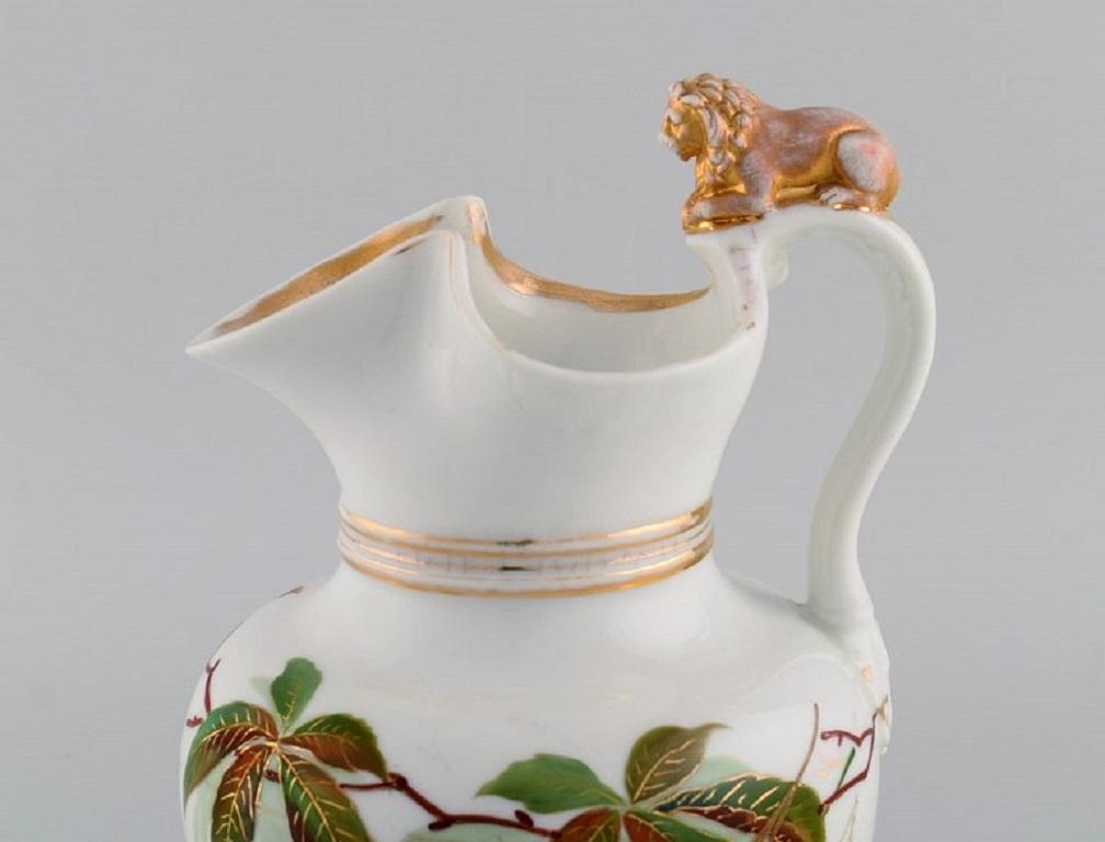 Antique Bing & Grøndahl chocolate jug in porcelain modelled with a lion on the handle. 
Hand-painted flowers and gold decoration. 1870s.
Measures: 25 x 17 cm.
In good original condition. Normal wear without chips or cracks.
Stamped.
