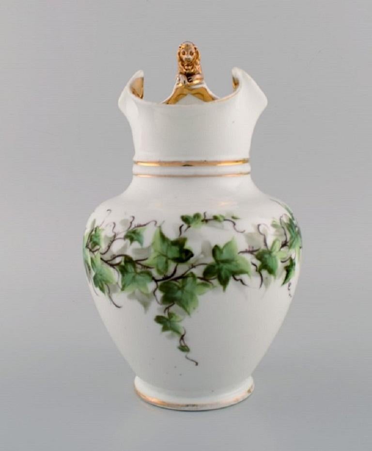 Antique Bing & Grøndahl chocolate jug in porcelain modelled with a lion on the handle. 
Hand-painted flowers and gold decoration. 1870s.
Measures: 24.5 x 17 cm.
In good original condition. Normal wear without chips or cracks.
Stamped.