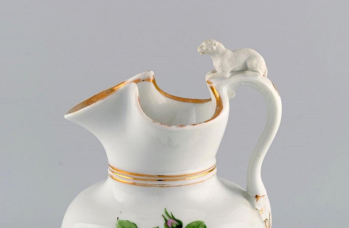 Antique Bing & Grøndahl chocolate jug in porcelain modelled with a lion on the handle. Hand-painted flowers and gold decoration. 
1870s.
Measures: 25 x 16 cm.
In good original condition. Normal wear without chips or cracks.
Stamped.