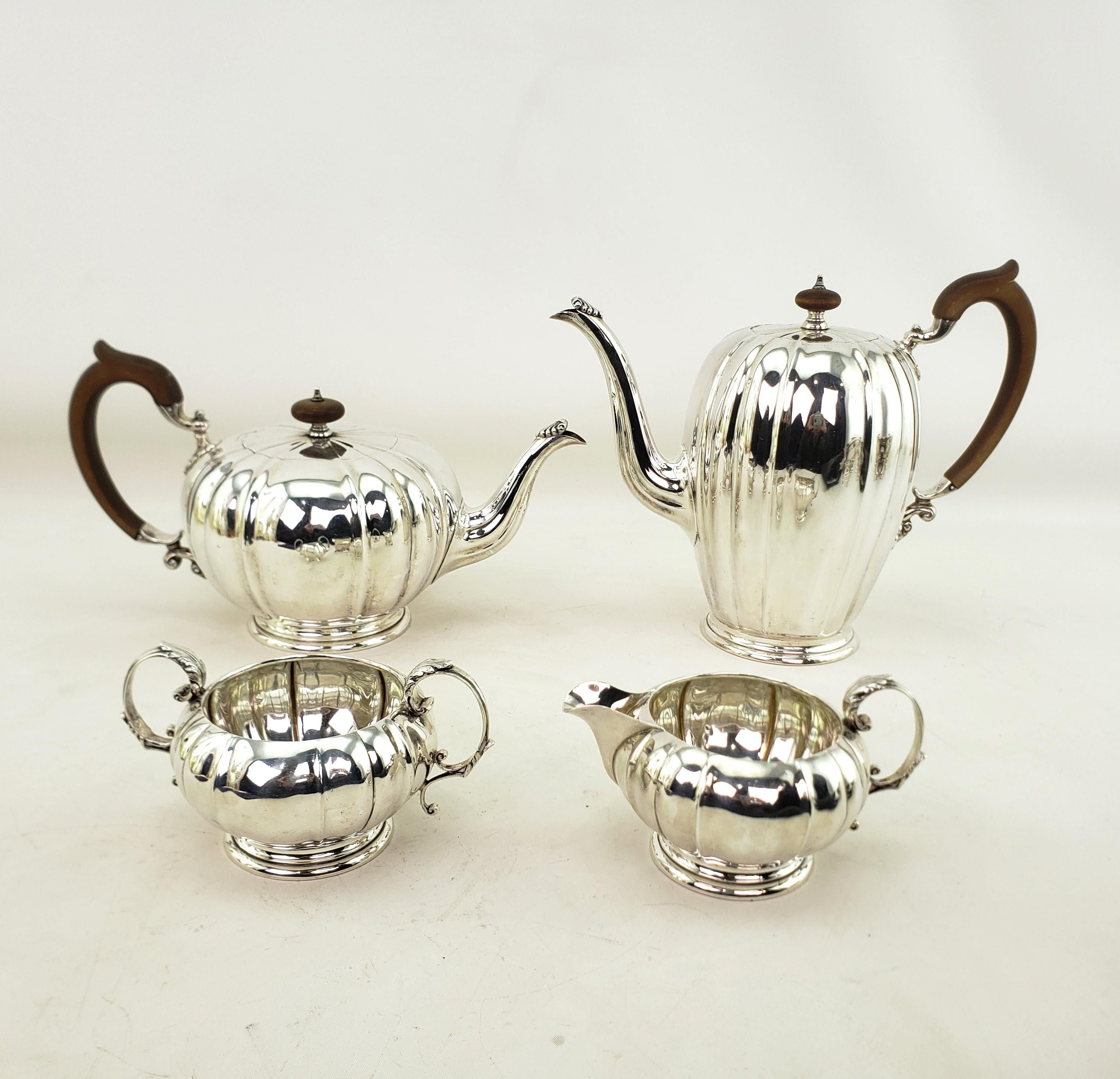 Tgus antique tea or coffee set was made by the renowned Henry Birks of Canada and dates to approximately 1920 and done in a Georgian style. This four piece set is composed of sterling silver with furrowed sides and stylized leaf accents. The coffee