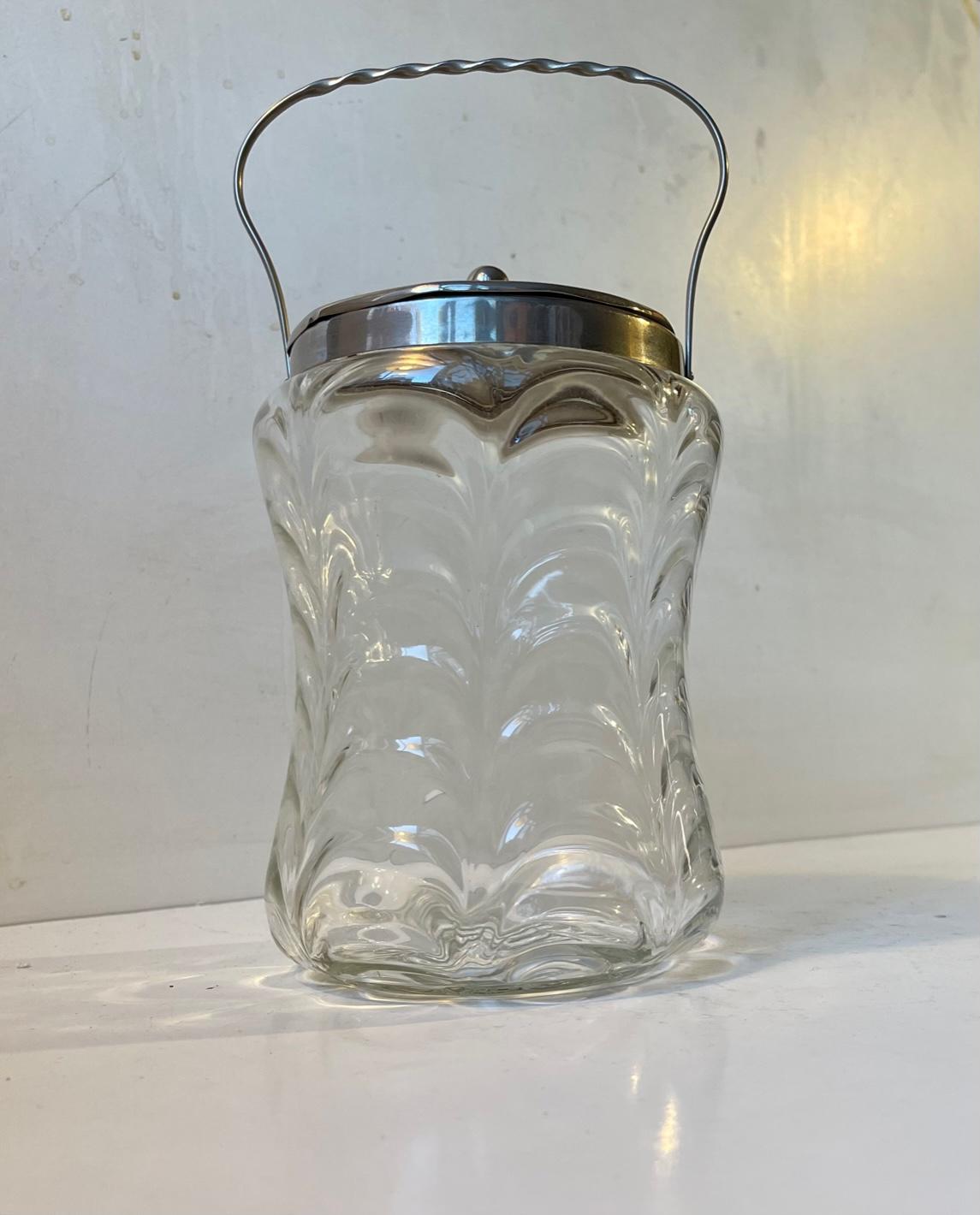 A mouth-blown biscuit jar in clear optical wavy glass. It features its original pewter lid and twisted handle. It was made circa 1900-1910 by Holmegaard in Denmark. Use it for its purpose or to store tea, coffee or rice etc. Measurements: height: