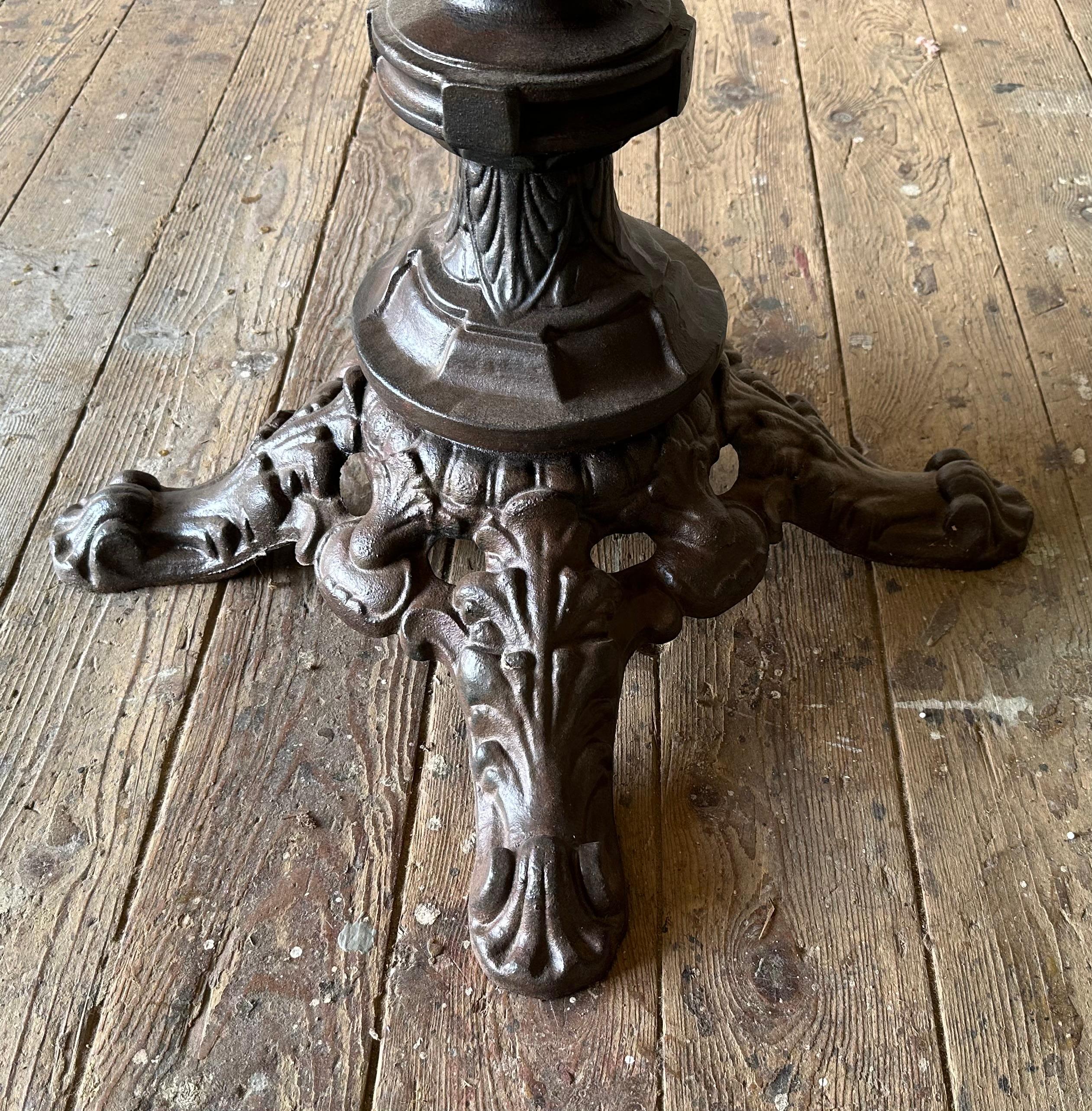 The French bistro table embodies a blend of rustic charm and refined elegance.  The white round vintage marble top dining table showcases exquisite veining patterns.  Although it has suffered some minor damage as shown in photos, in many ways it