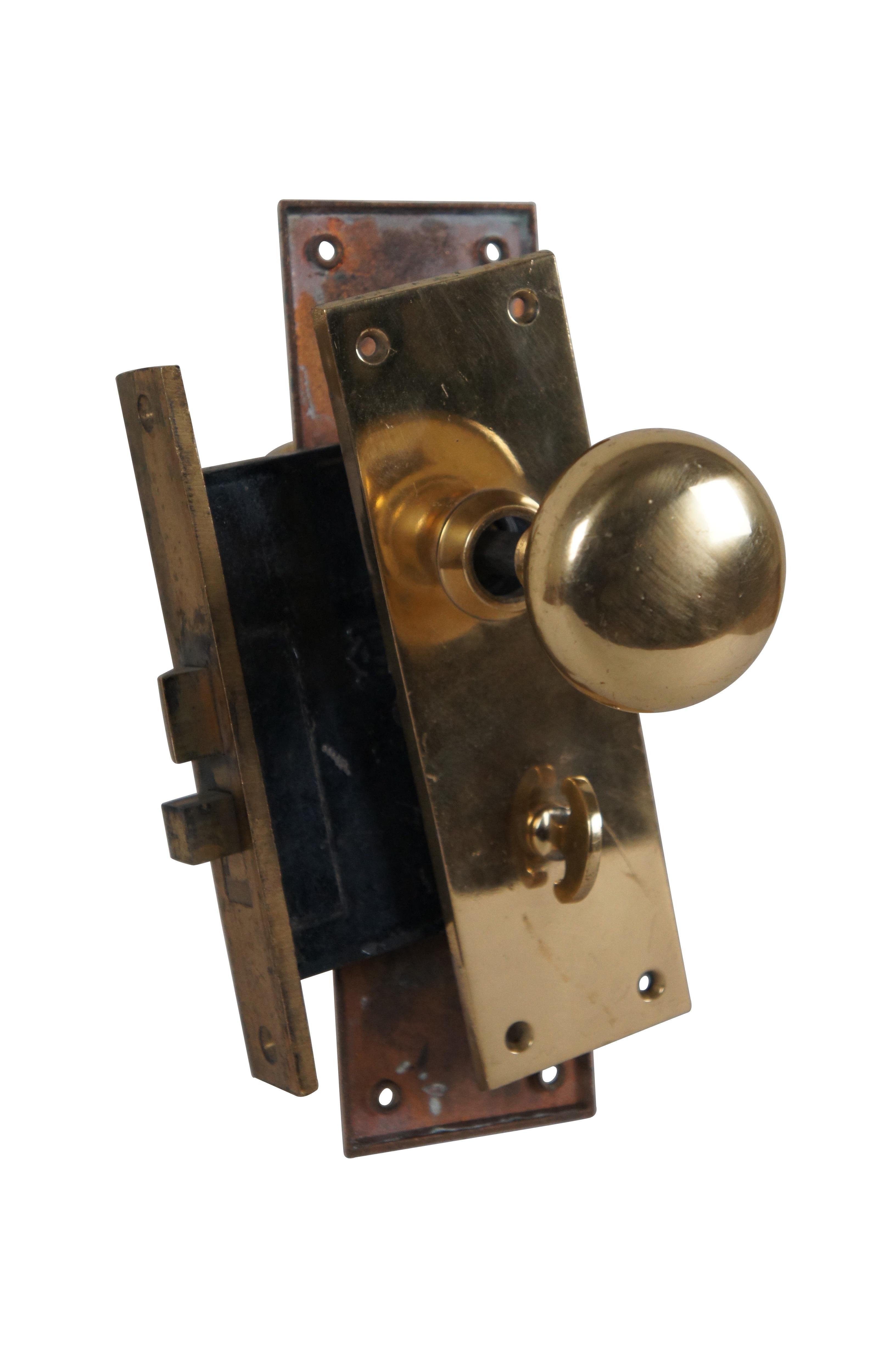 Late 19th - early 20th century reclaimed entry door lockset featuring heavy brass plates, round knobs, and an un-keyed manual dead bolt type latch, only accessible from one side of the door. Knob and latch mechanisms in functional condition.
