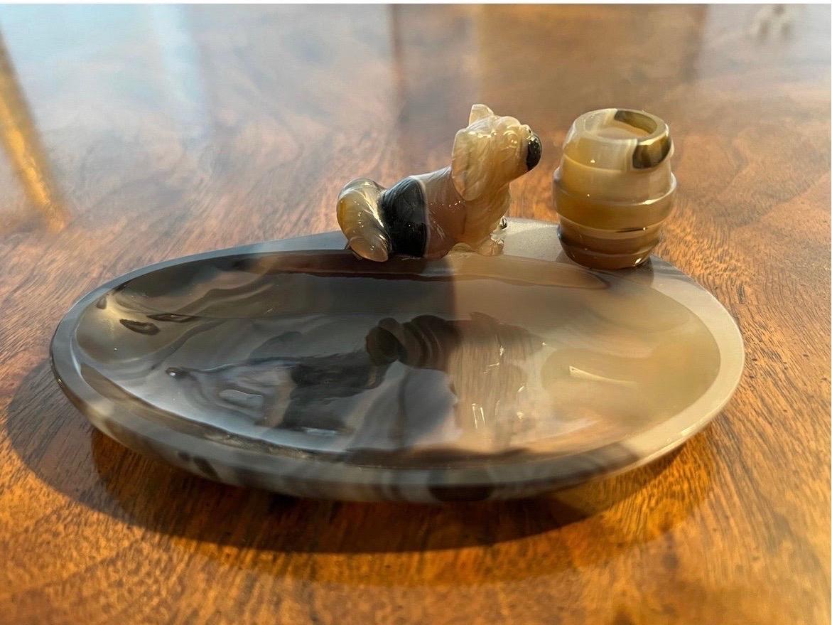 This is an extremely unique and beautiful piece. Having a deep toned black agate ashtray bowl, finely carved Pekingese dog and barrel (match holder) form mount to edge and match strike to side.

Very finely made, i believe it is possible Russian
