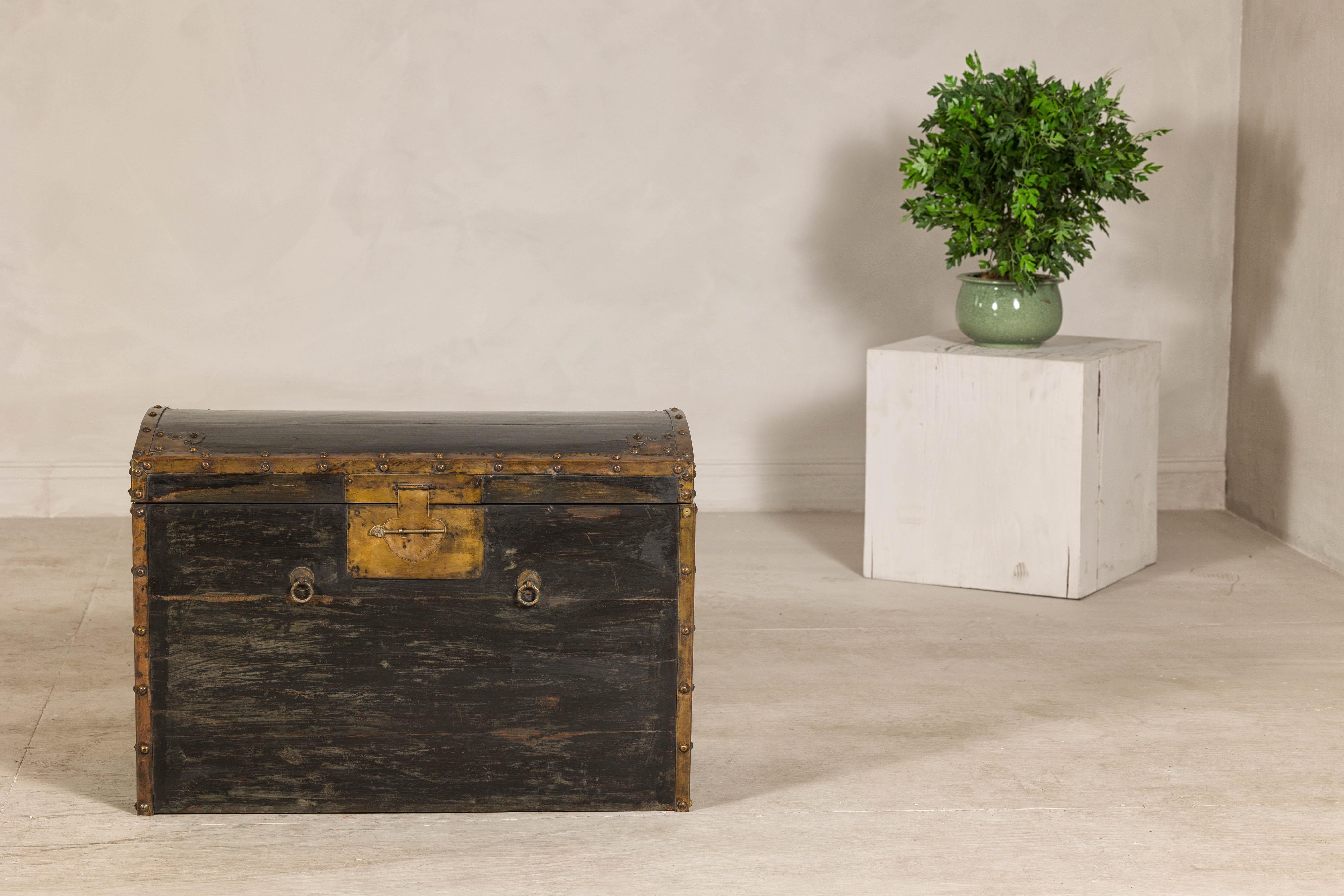 Baule nero e oro della tarda dinastia Qing con coperchio a cupola e minuteria in ottone. Questo baule nero e oro con piano curvo è un notevole esempio di antico artigianato cinese, che unisce un design senza tempo a una pratica conservazione. Il