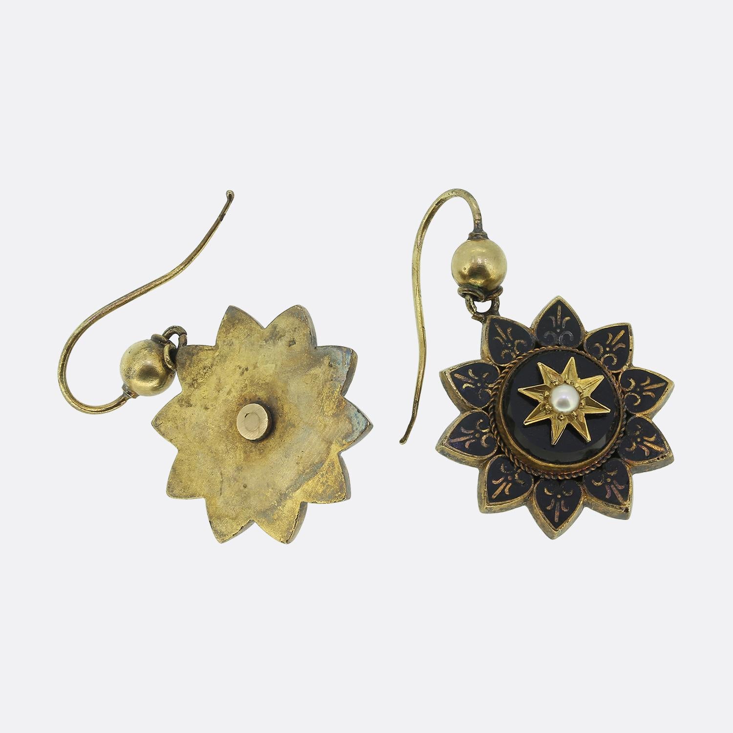 Here we have a fabulous pair of Victorian drop earrings, each meticulously crafted from 15ct yellow gold. The design features a floral motif with neat black enamelling and a pearl set onyx at the centre. The earrings feature a nice aged patina and
