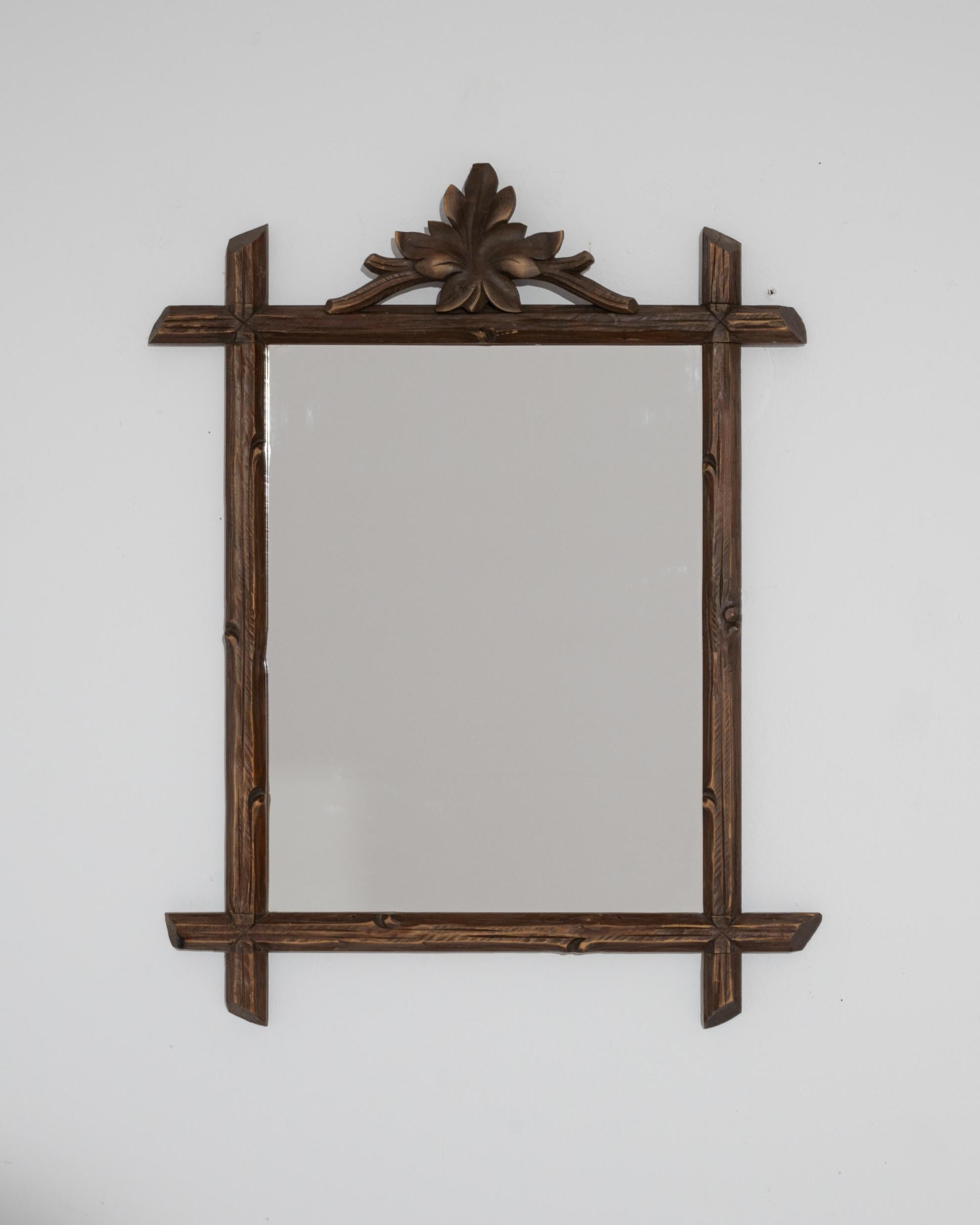The eye-catching design of this vintage wooden mirror conjures the fresh
 air of alpine abundance. Crafted in Austria at the turn of the century, the wooden frame creates a masterful illusion of rustic simplicity — carved to resemble an arrangement