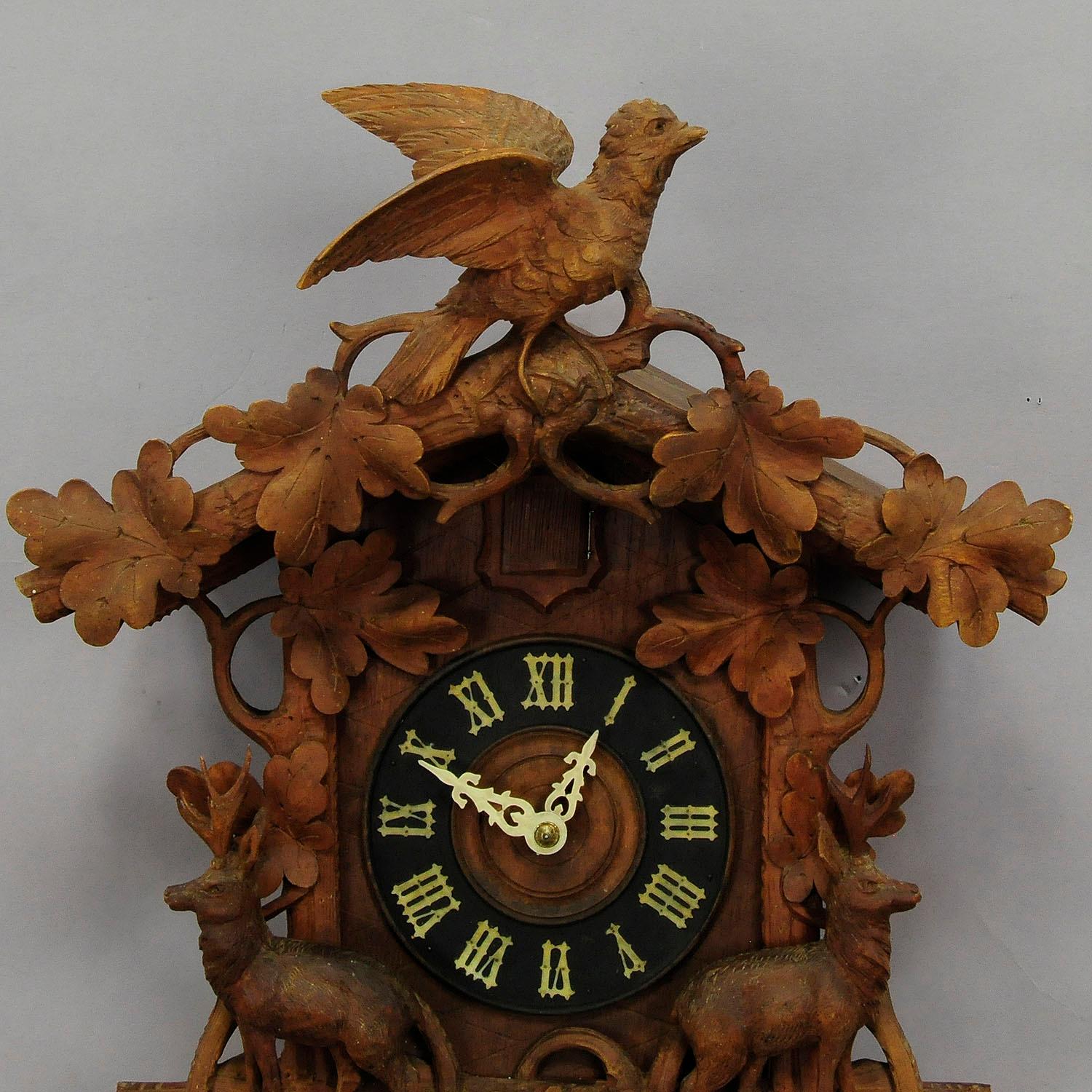 A detailed hand carved wooden cuckoo clock, decorated with branches, oak leaves, two deers and a bird on top. Black Forest, Germany, circa 1900. Clockwork in working condition, overworked by a clockmaker.

Measures: Width 15.35
