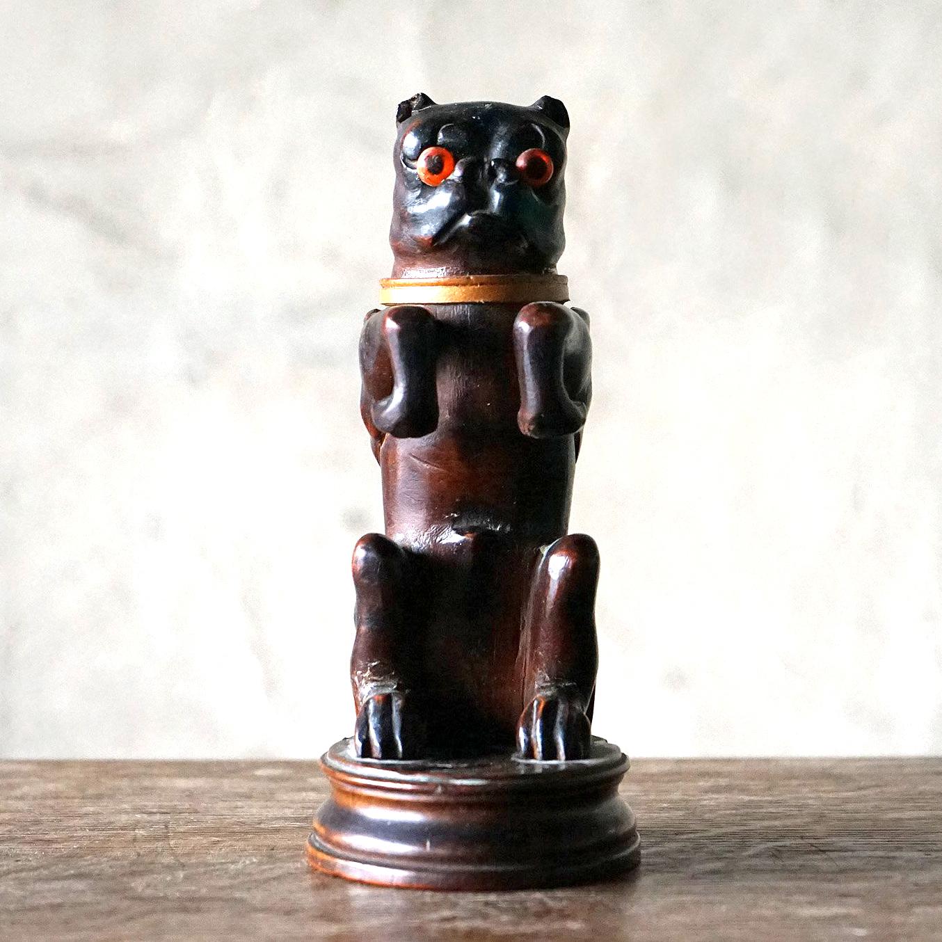 Antique Carving in the Form of a Dog

Raised up on his hind legs, the head with original glass eyes tilts back to reveal the original glass inkwell inside. The arms are curved round so he can hold a pen.

Probably carved from linden wood.

It is in