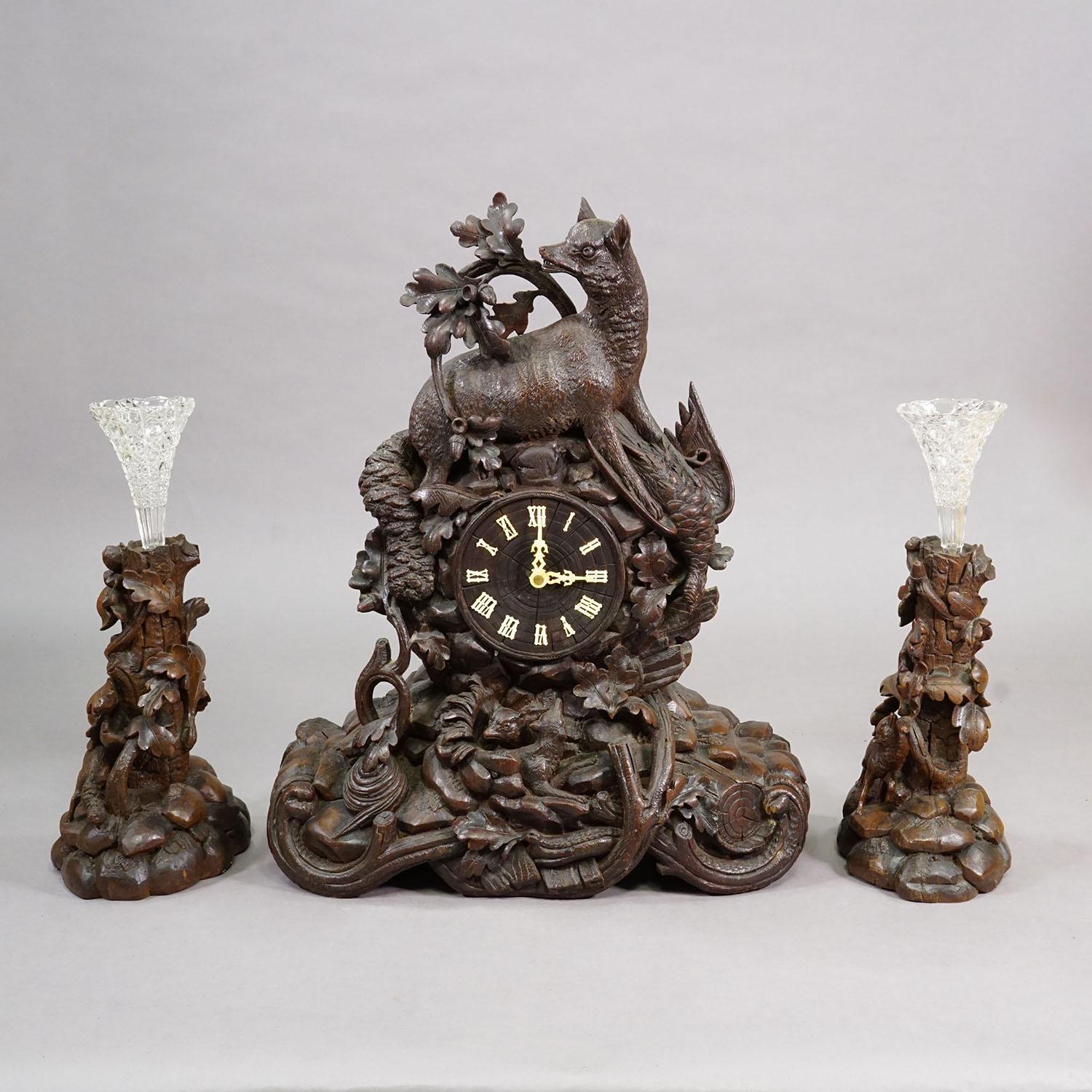 Horloge ancienne Black Forest avec motifs de chasse sculptés, vers 1900

Cet ensemble d'horloges anciennes de la Forêt-Noire, daté d'environ 1900, comprend une horloge de cheminée sculptée et deux pièces latérales assorties avec des motifs de