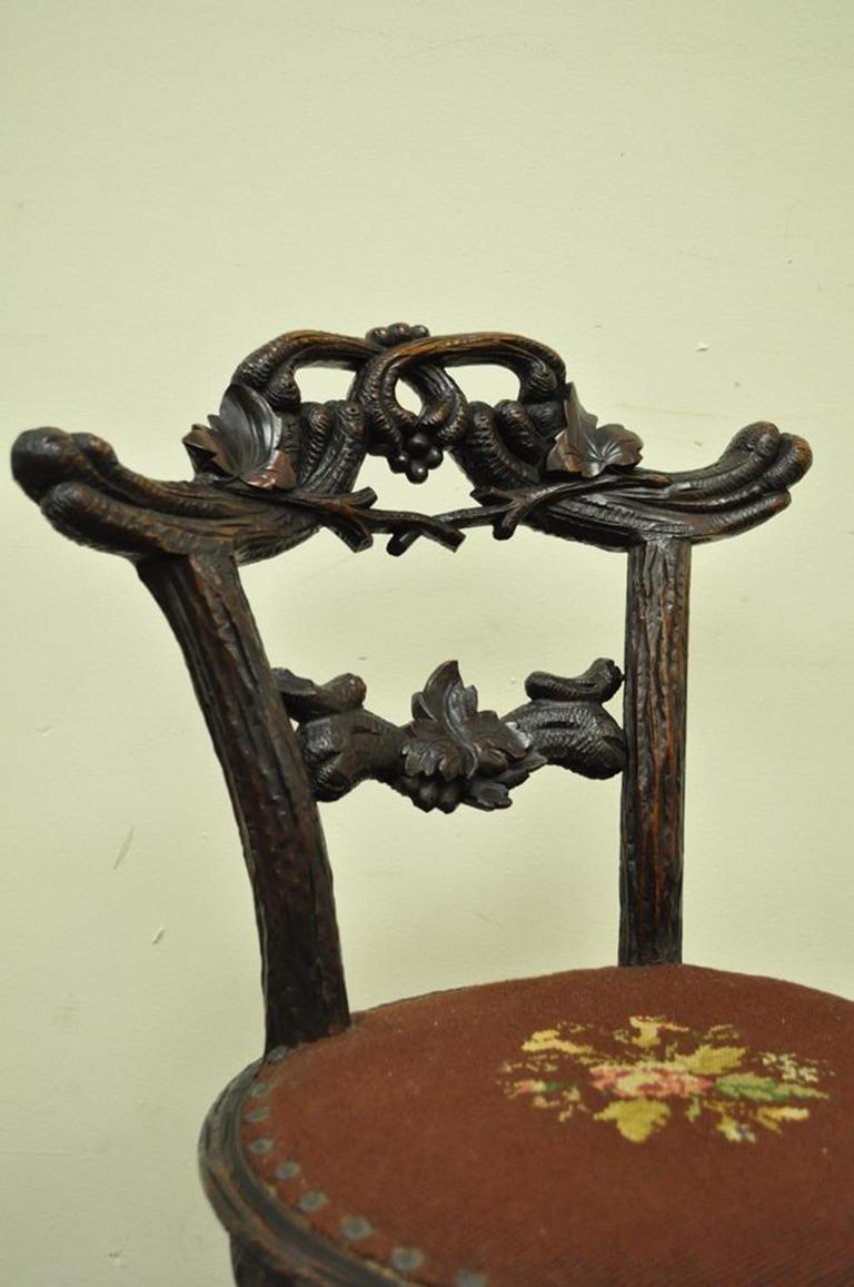 Beautiful antique black forest carved mahogany, faux bois, small side chair or vanity chair. Item features an intricately carved faux bois design complete with realistic leaves, as well as a lovely needlepoint seat with nailhead trim, circa mid-late