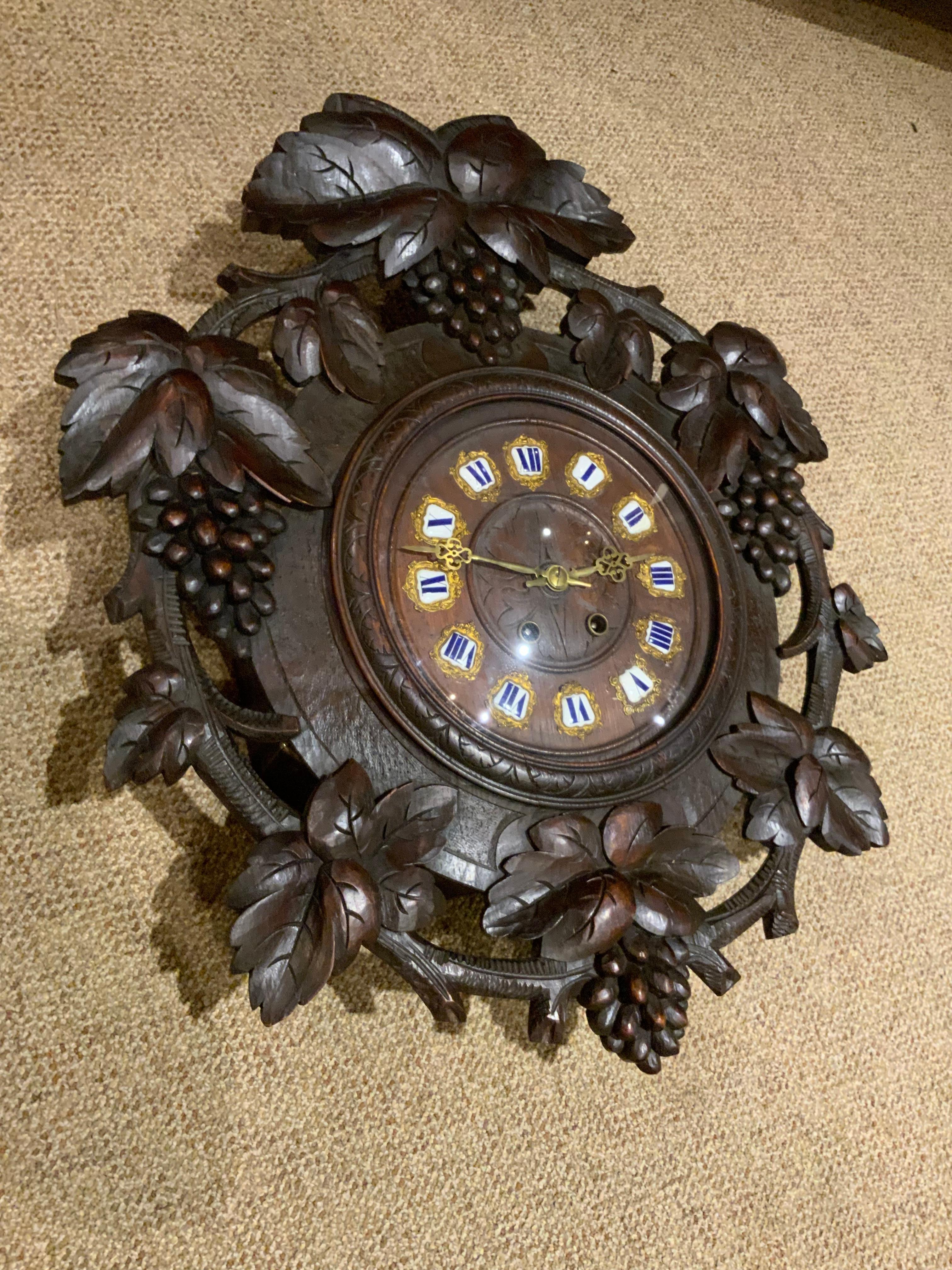 This handsome clock is beautifully carved with grapes and oak leaves
Around the face of the clock. It has the key and pendulum and
The spring is good. The face lifts for winding. The numerals are in
A white and blue enamel. This type carving is