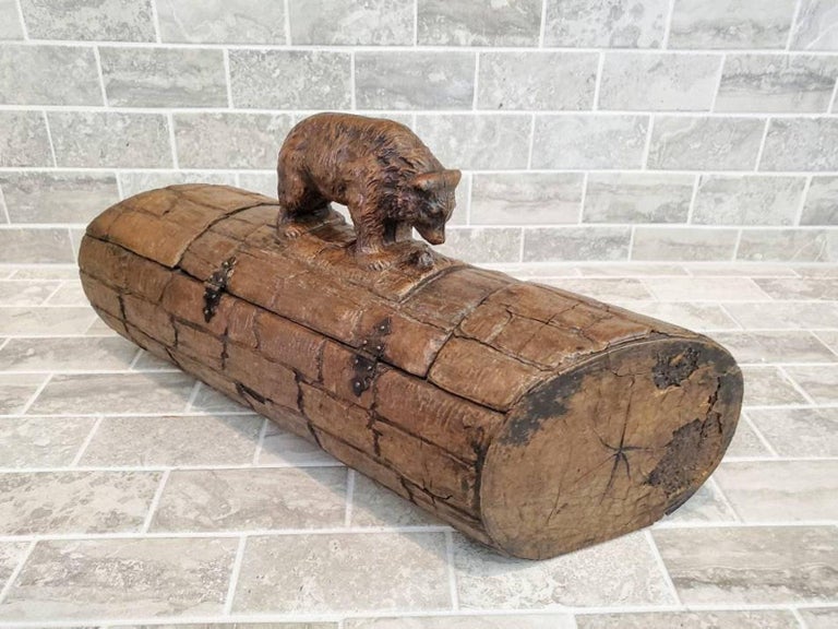 A fine quality antique Swiss Black Forest ware, featuring a rustic naturalistic intricately hand carved wooden box in the shape of a log, surmounted by a highly detailed figural bear statue carving atop a hinged lid, with small metal lock in the