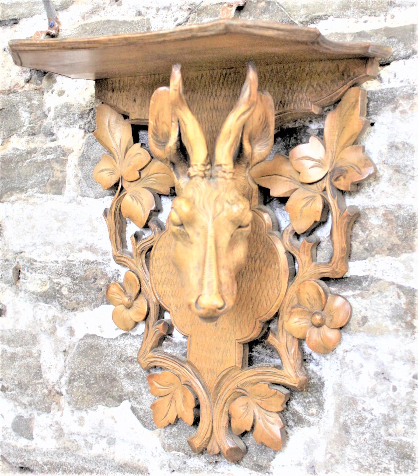 This very ornately hand carved wall shelf was made in Europe, and most likely Germany, in approximately 1900 in the Black Forest style. The shelf is composed of a softwood and features a large and detailed hand carved red deer head mounted to a back