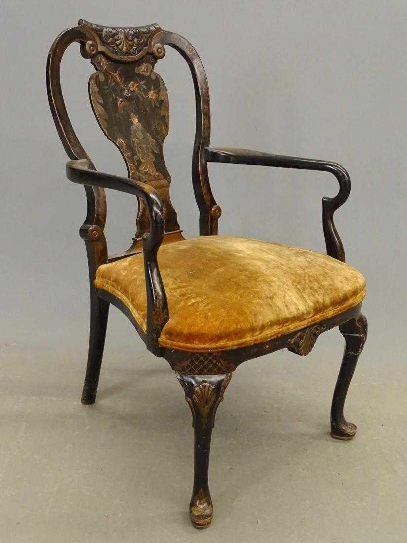 The antique black Japanned armchair in the Queen Anne style with upholstered seat is decorated with a Oriental figure crossing a bridge with a flowering branch overhead. The knees of the cabriole legs are embellished with stylized shells as is the
