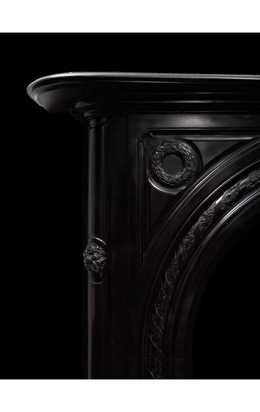 A large antique black marble fire surround from the early Victorian period.

A sizable serpentine shaped mantelpiece with moulded edges, curves forward over the keystone. The recessed panelled keystone connects two arches, these are beautifully