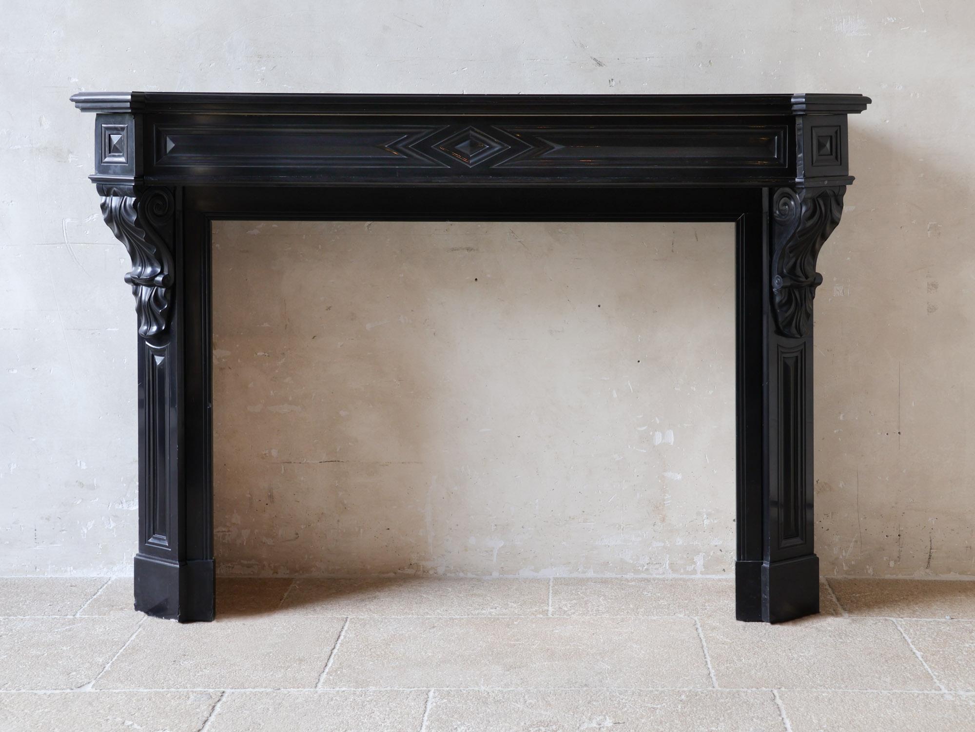 Antique black marble mantelpiece, model Modillion, from the late 19th century. This fireplace is richly decorated with acanthus leaves on and under the consoles, diamond cut panels in the front and double profiled fireplace top. The sleek lines of