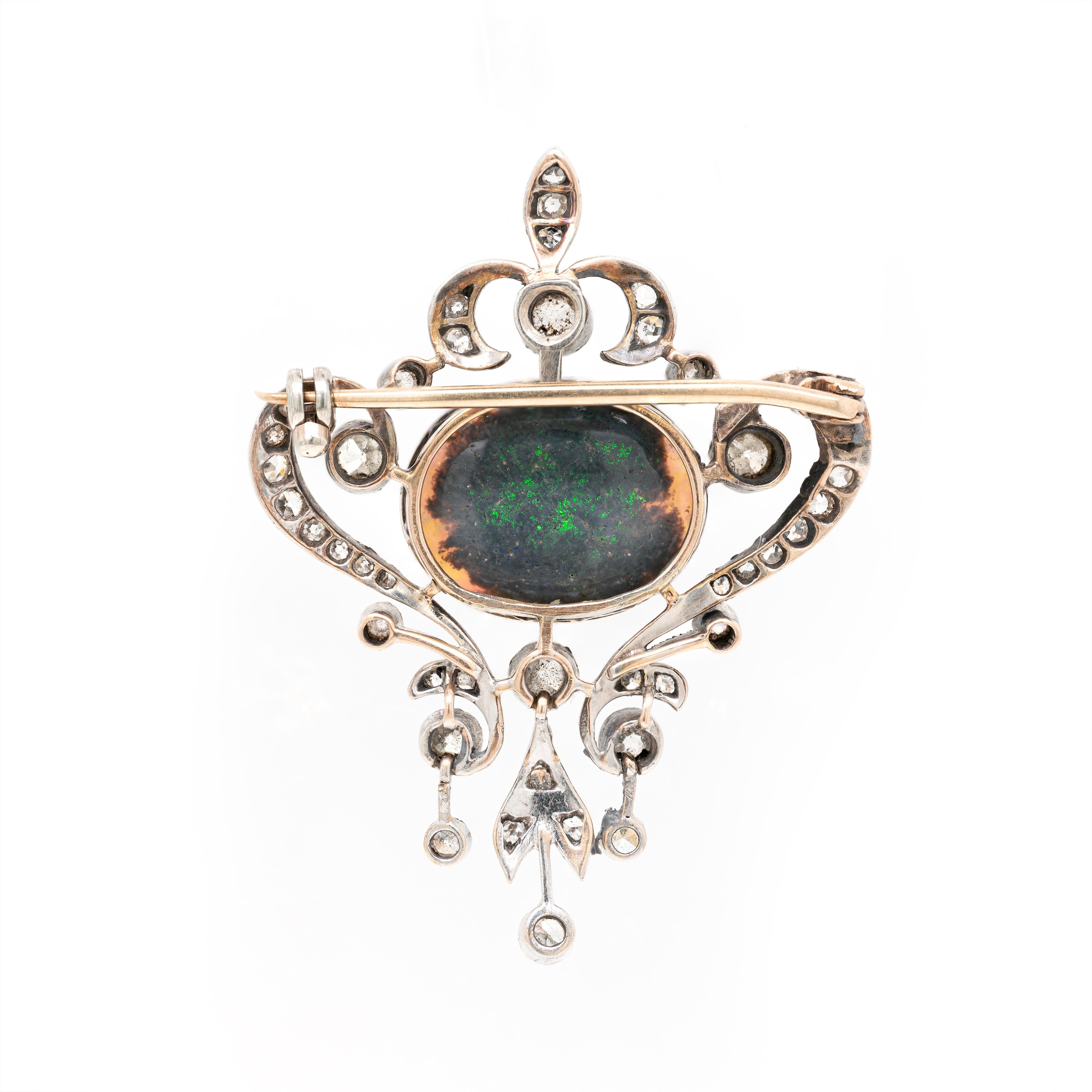 This fabulous antique brooch, masterfully designed with elegant Art Nouveau accents, features a wonderful black opal cabouchon measuring 20 x 17mm, rub-over set in the centre in an 18 carat yellow gold open back mount. The spectacular opal is