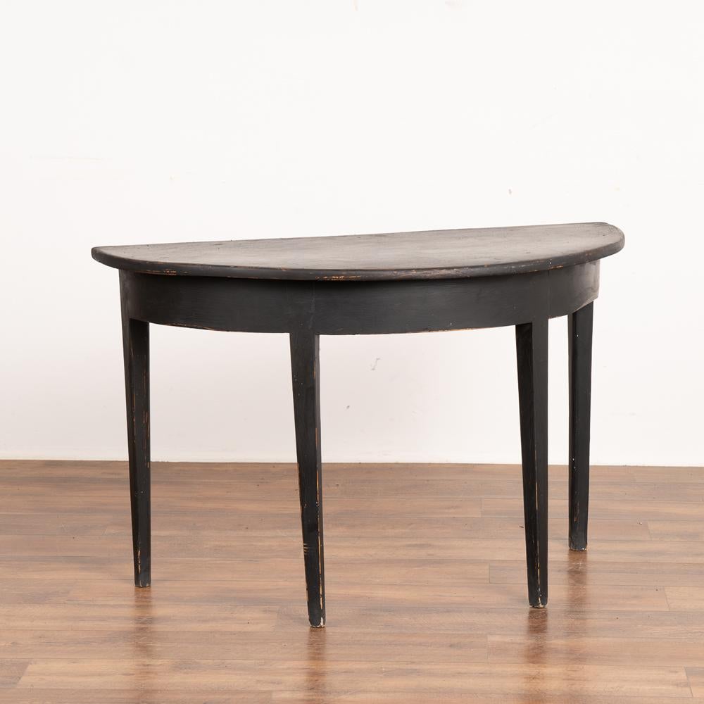 Single pine demi-lune side table with simple Swedish country design and gently tapered legs.
Newer professionally applied black painted finish, slightly distressed to fit age and grace of this console.
Restored, strong and stable. Any old nicks,