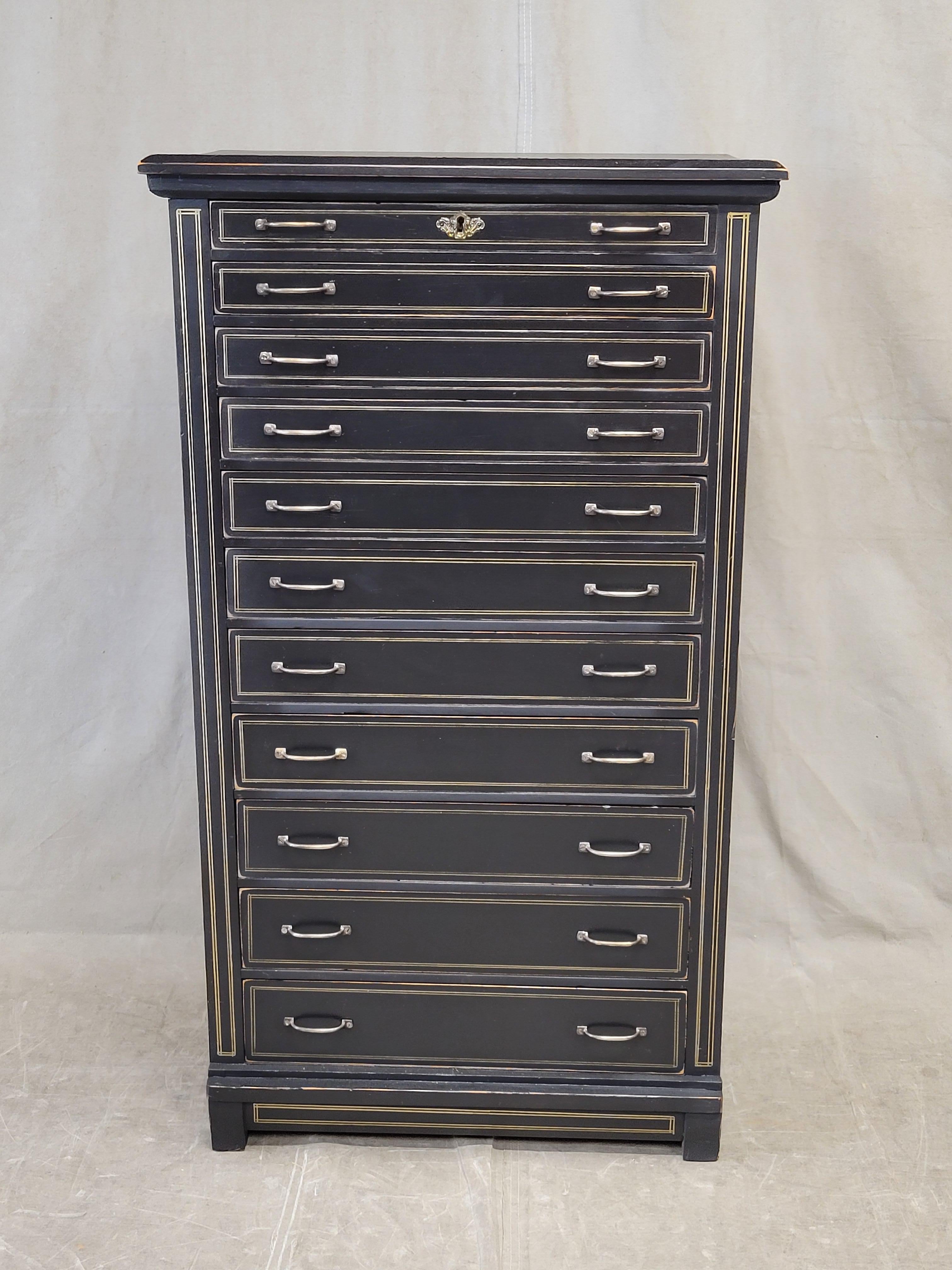 A classic English styled antique pine black painted eleven drawer lingerie tall chest with gold French line motif and brass hardware. Built by a skilled craftsman with eleven graduated drawers and hand-cut dovetails. This piece has been