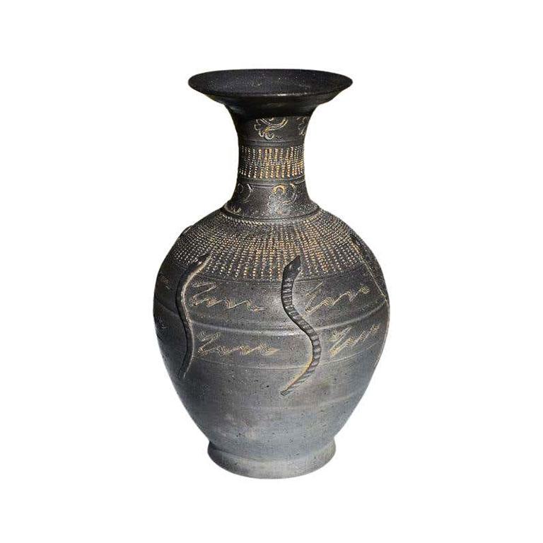 A unique mat-black etched vase with a snake motif. This beautiful vessel is hand-crafted and decorated around the body with textured snakes around the side. It has a marvelous texture and will be a wonderful addition to any tabletop. Mix and match