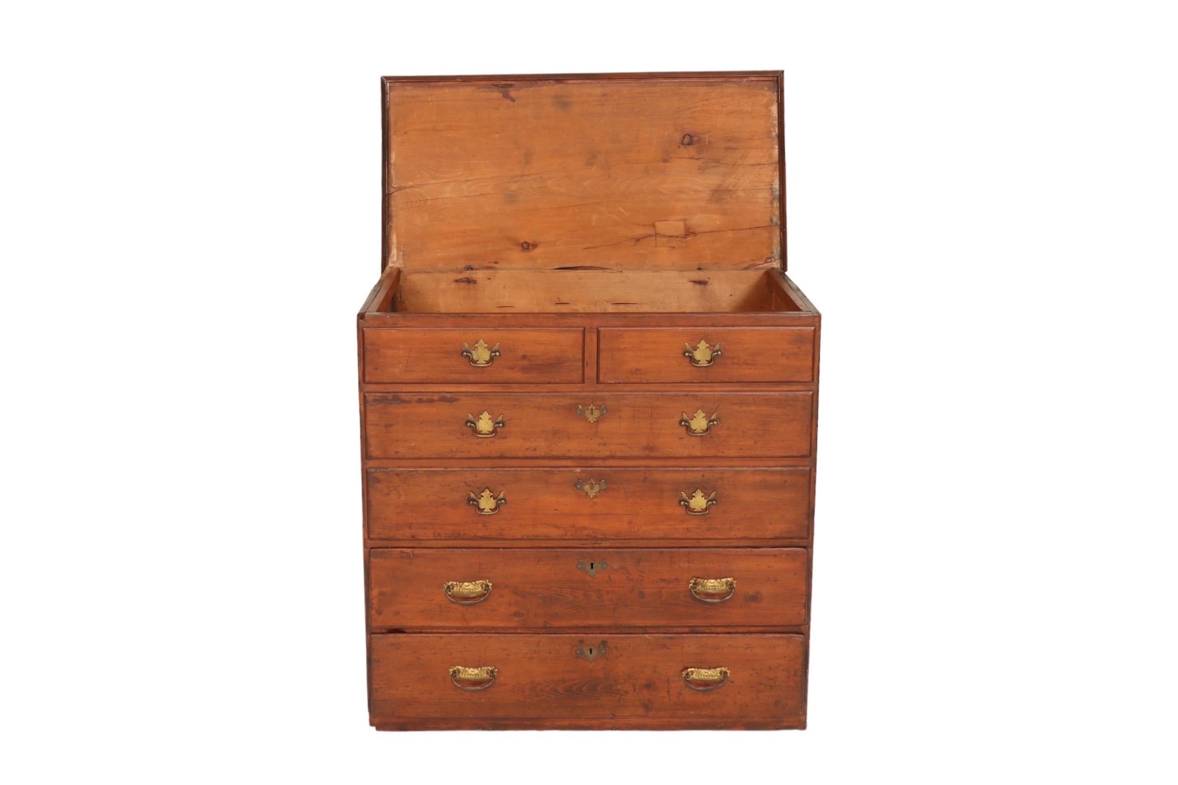 An antique pine blanket chest dated 1763 on the back. The rectangular top with beveled trim opens to reveal a deep storage compartment. The face has two small sham drawers over two long sham drawers, with two functional dovetailed drawers below, all