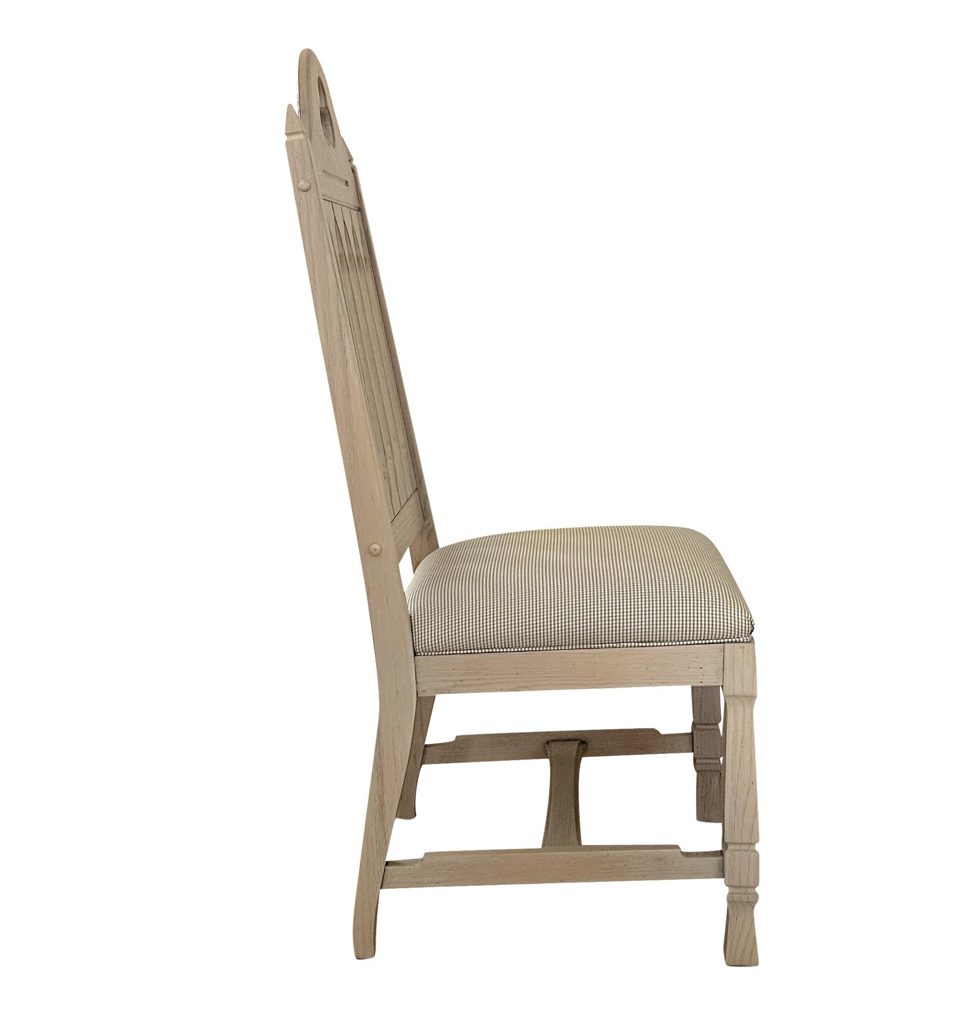 A set of six (6) hand-carved antique gothic dining chairs, which have been newly refinished and reupholstered. A bleached finish is paired with Schumacher' Barnet Cotton Check-Nickel. The combination of finish and fabric effuses a freshness, adding