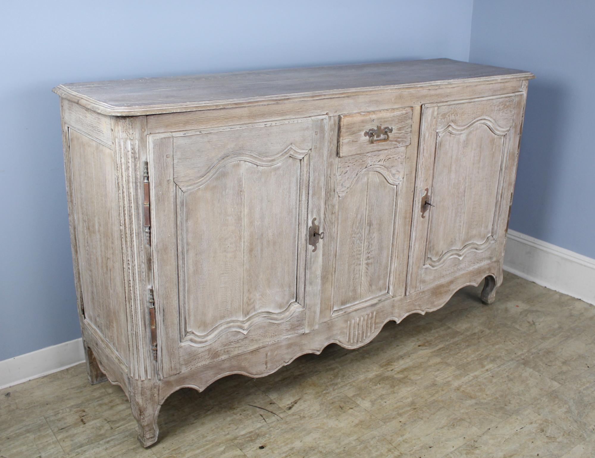 Wonderful Classic French oak buffet made modern with bleaching. The doors are well paneled as are the sides. There is a simply shaped apron. Feet are well-shaped also. Small center drawer for extra storage, and the reeded vertical quarter columns at